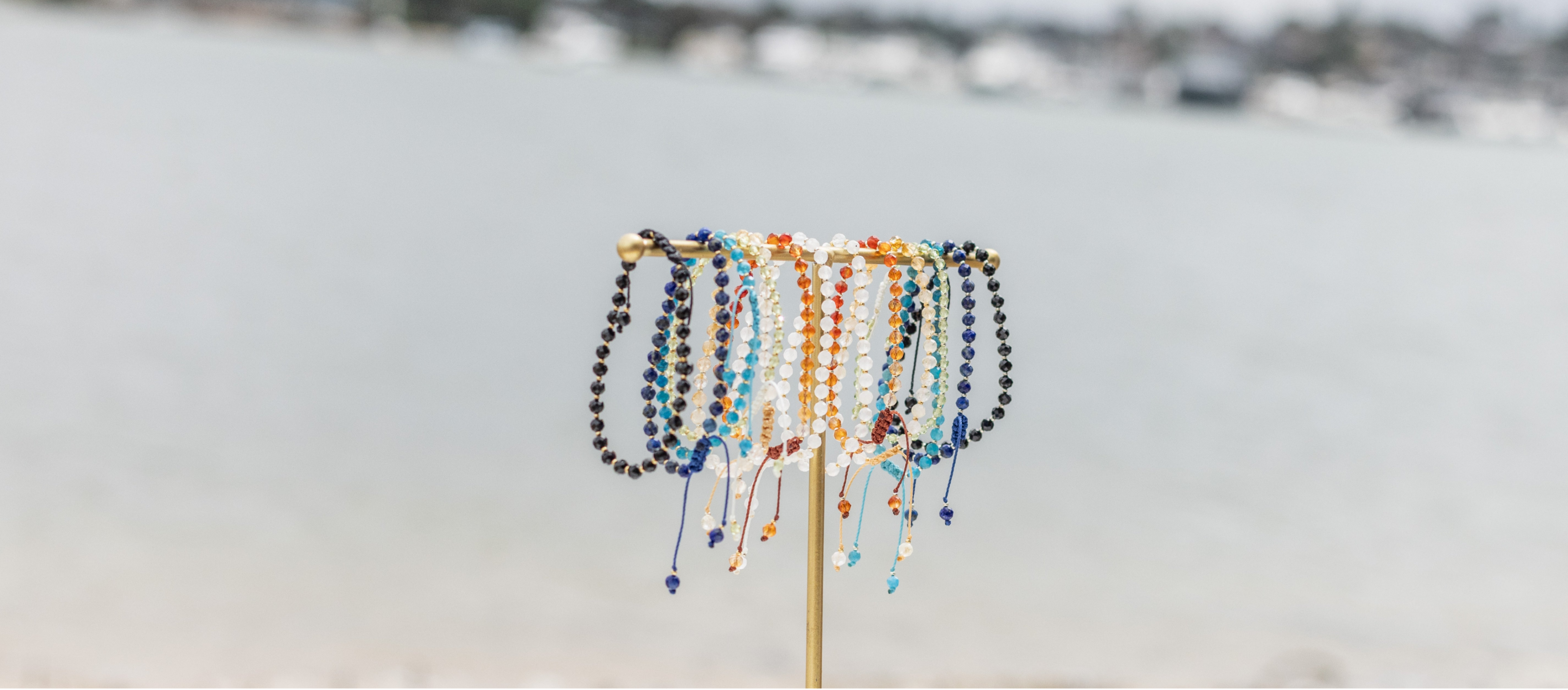 Apatite Black tourmaline lapis lazuli citrine carnelian moonstone peridot bracelets on display on the beach zoomed out