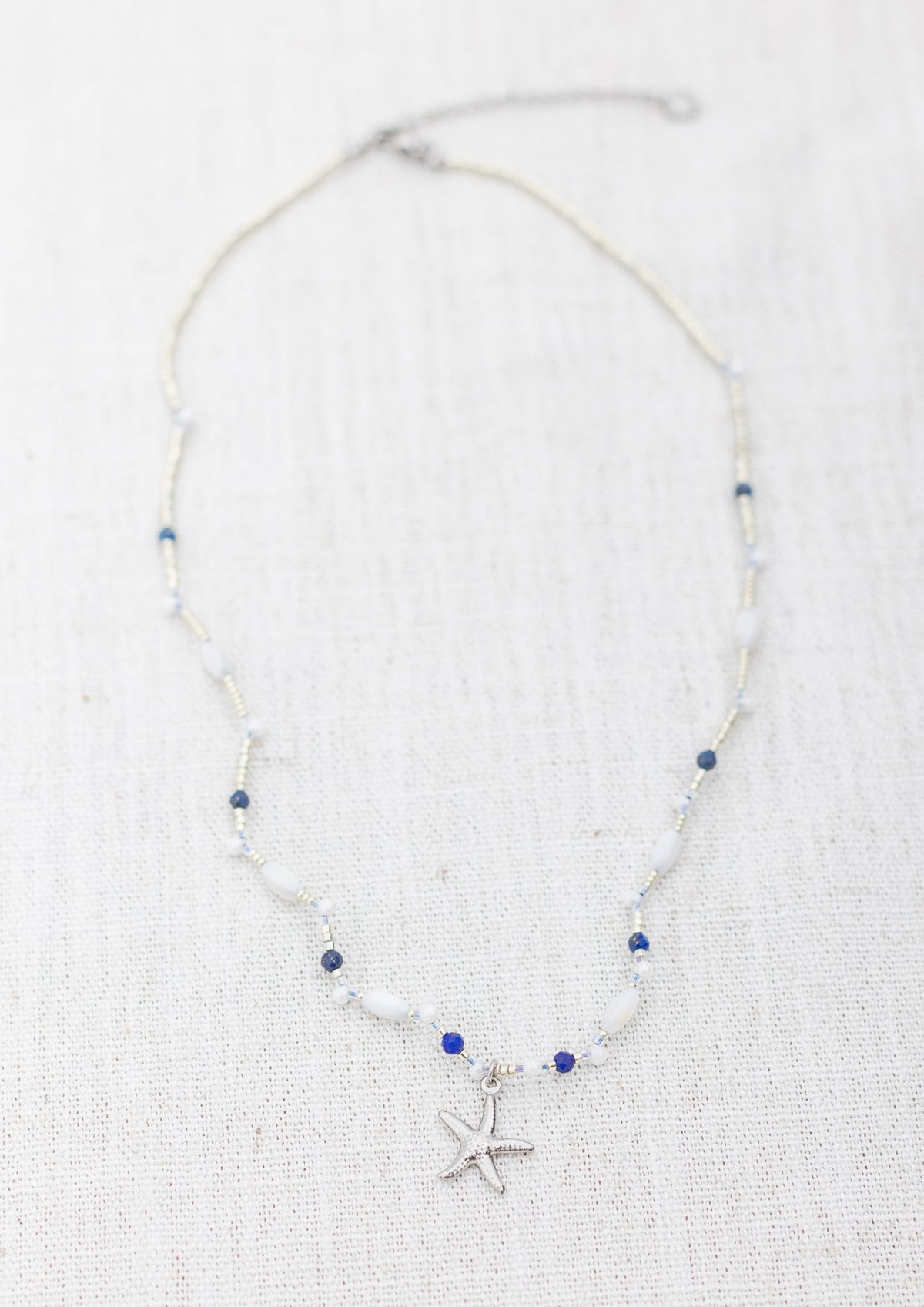 Intuitive Charms Amphitrite's Song Lapis Lazuli Braided natural Crystal beaded custom Bracelet in silver on a light fabric background rectangle version