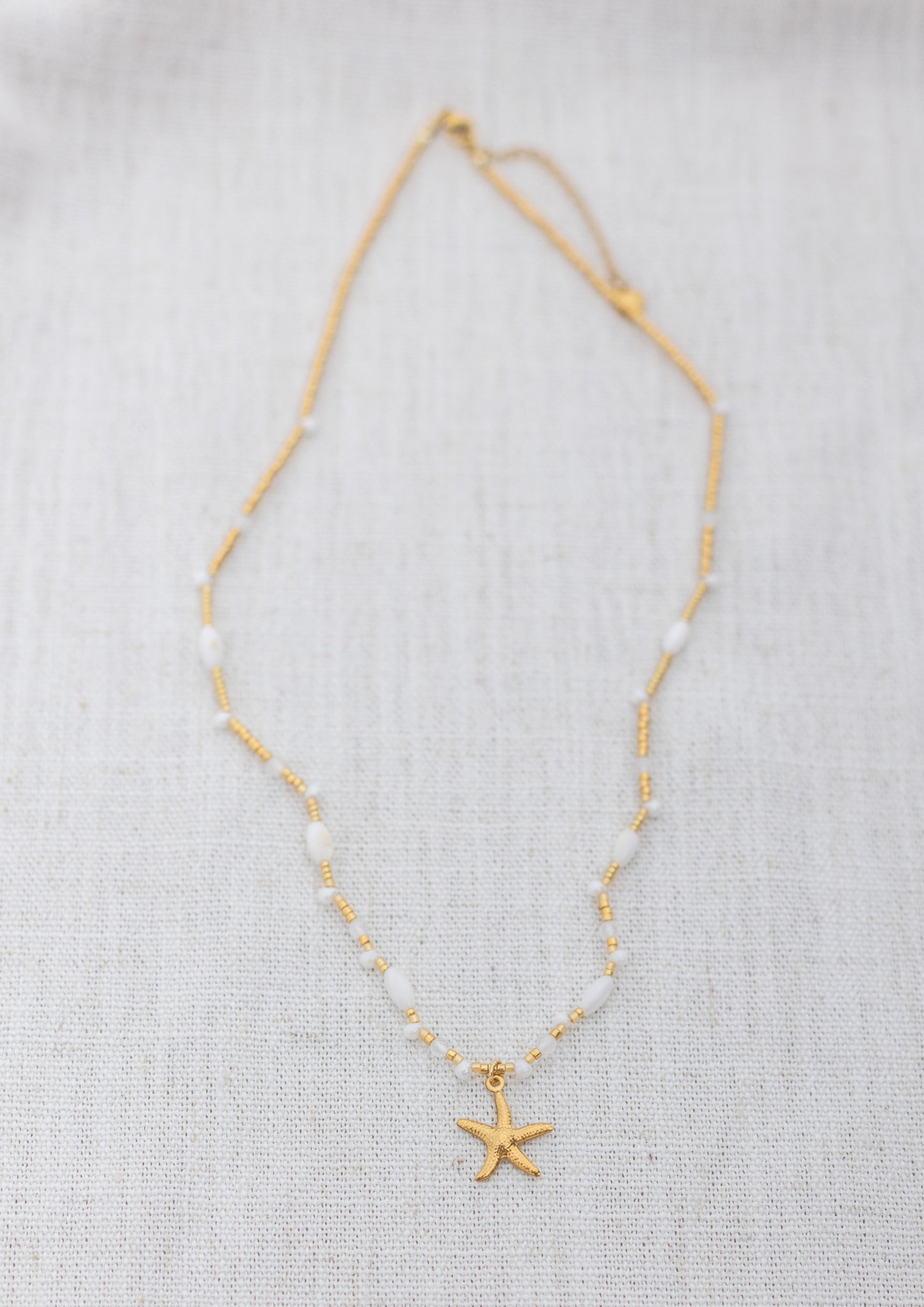 Intuitive Charms Selene's Song Moonstone natural Crystal beaded custom necklace in gold and clasp extension on a light fabric background rectangle view