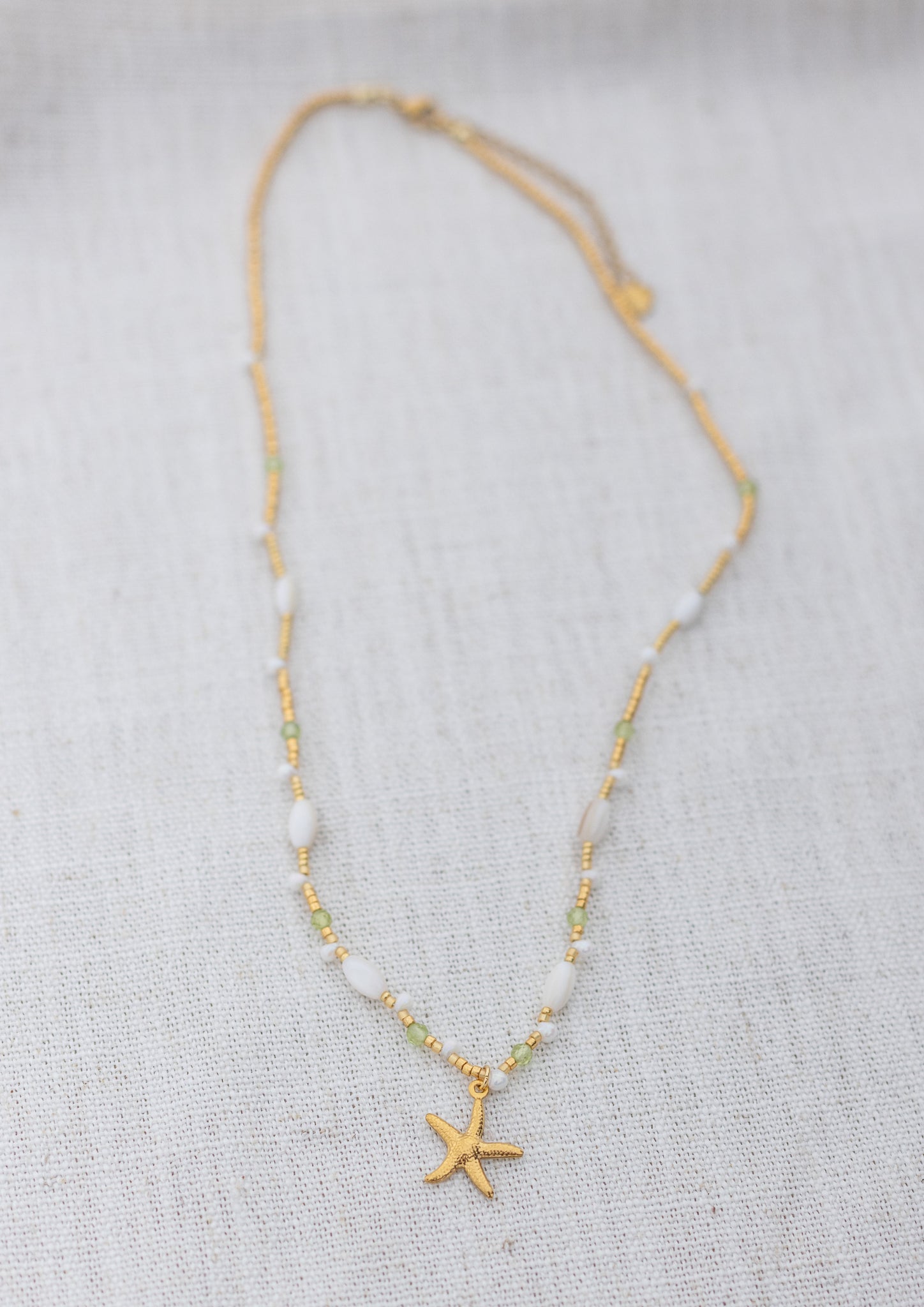 Intuitive Charms Nerina's Song Peridot natural Crystal beaded custom Bracelet in gold on a light fabric background rectangle version