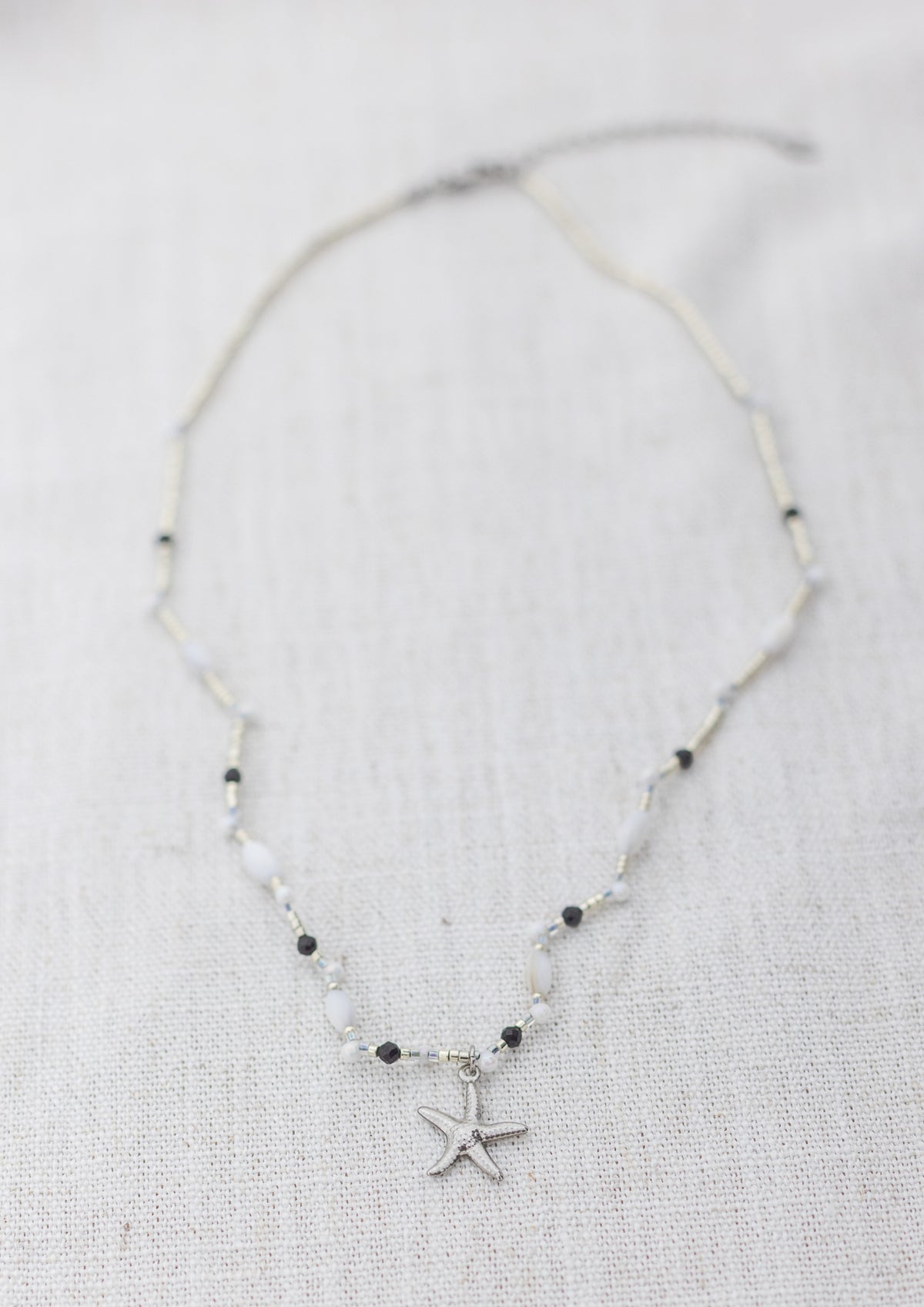 Intuitive Charms Ceto's Song Black tourmaline Braided natural Crystal beaded custom necklace in silver and black cord on a light fabric background rectangle version