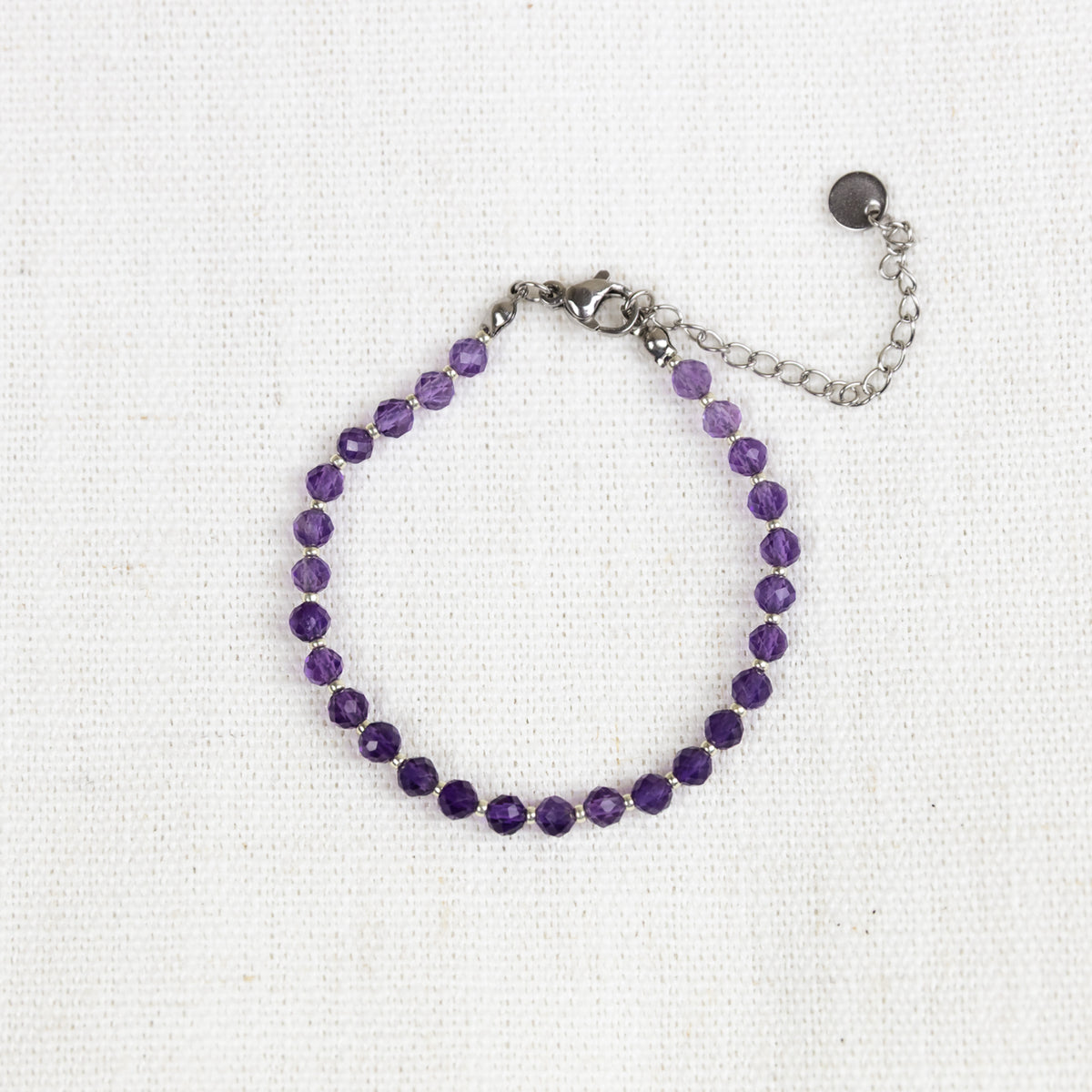 Intuitive Charms Sophia's Glow Amethyst Braided natural Crystal beaded custom Bracelet in silver and purple cord and stainless steel clasp extension on a light fabric background