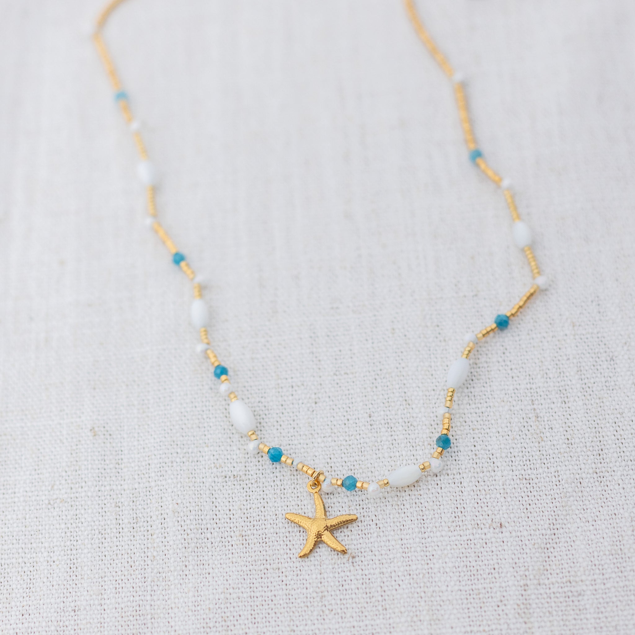 Intuitive Charms Delphina's Song Apatite Braided natural Crystal beaded custom necklace in gold on a light fabric background