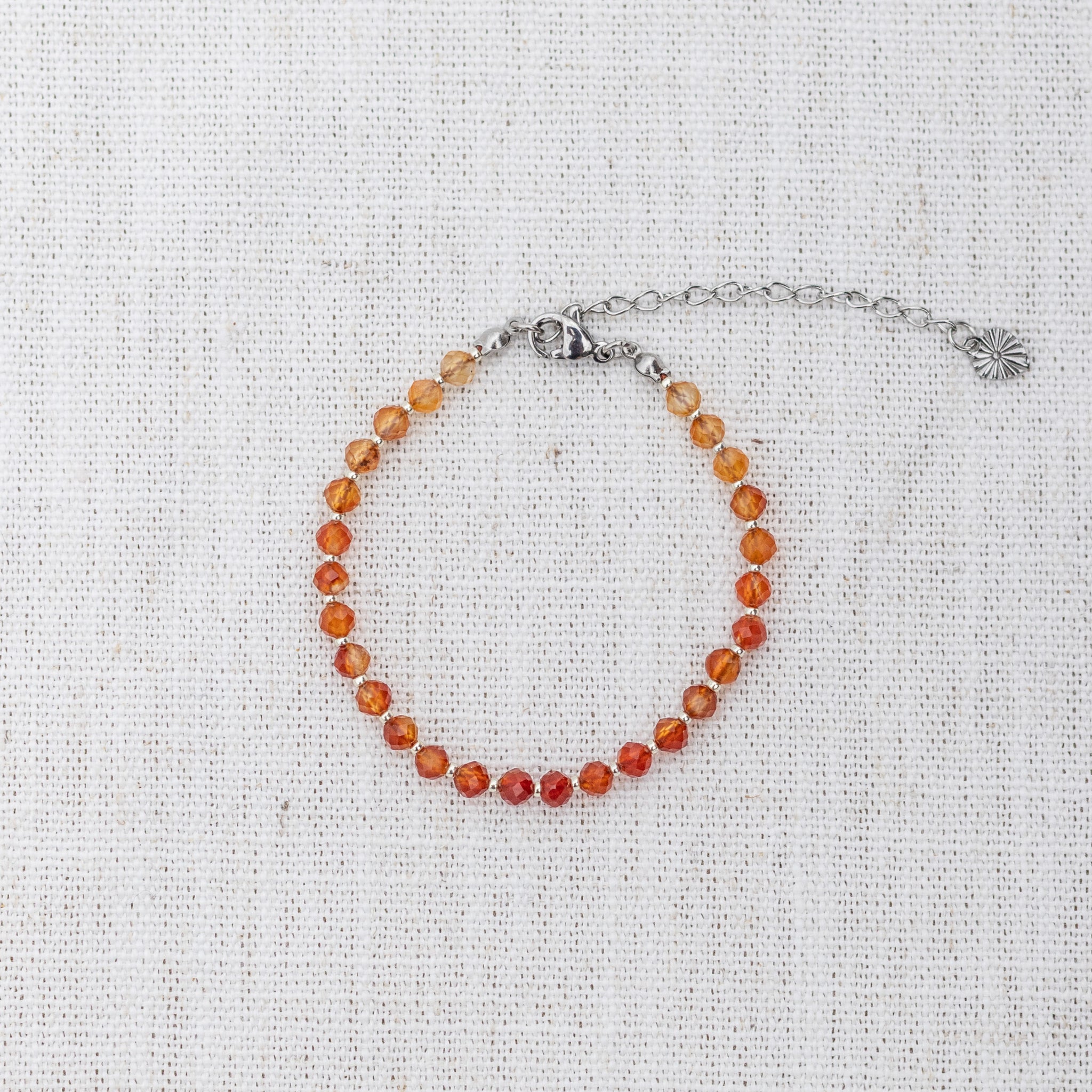 Intuitive Charms Coralia's Glow Carnelian Braided natural Crystal beaded custom Bracelet in silver and red cord and clasp extension on a light fabric background
