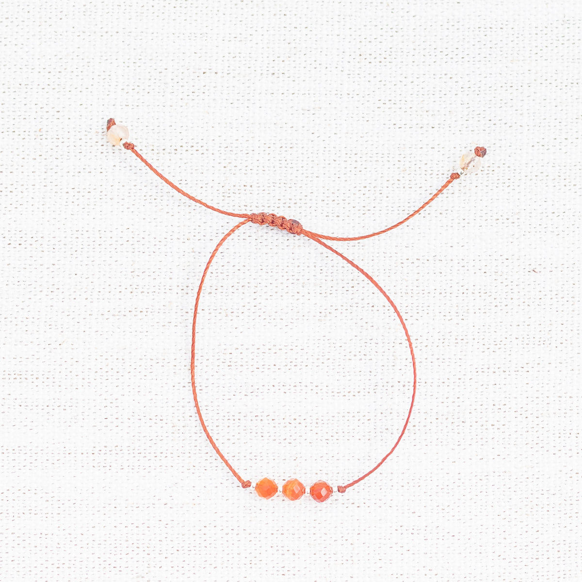 Intuitive Charms Coralia's Mist Carnelian Braided natural Crystal beaded custom Bracelet in silver and red cord on light fabric background