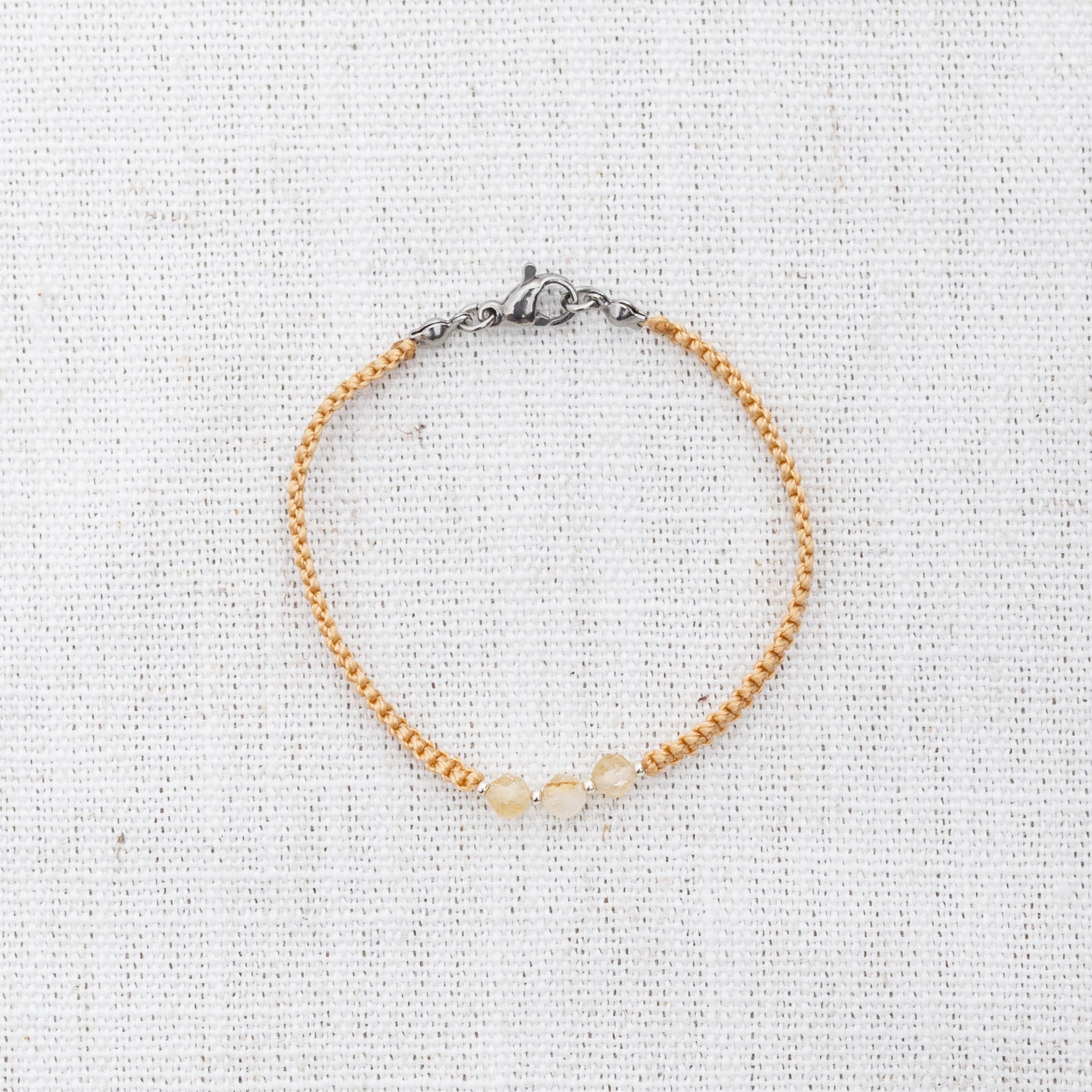 Intuitive Charms Eos's Guard Citrine Braided natural Crystal beaded custom Bracelet in silver and yellow cord and clasp on a light fabric background