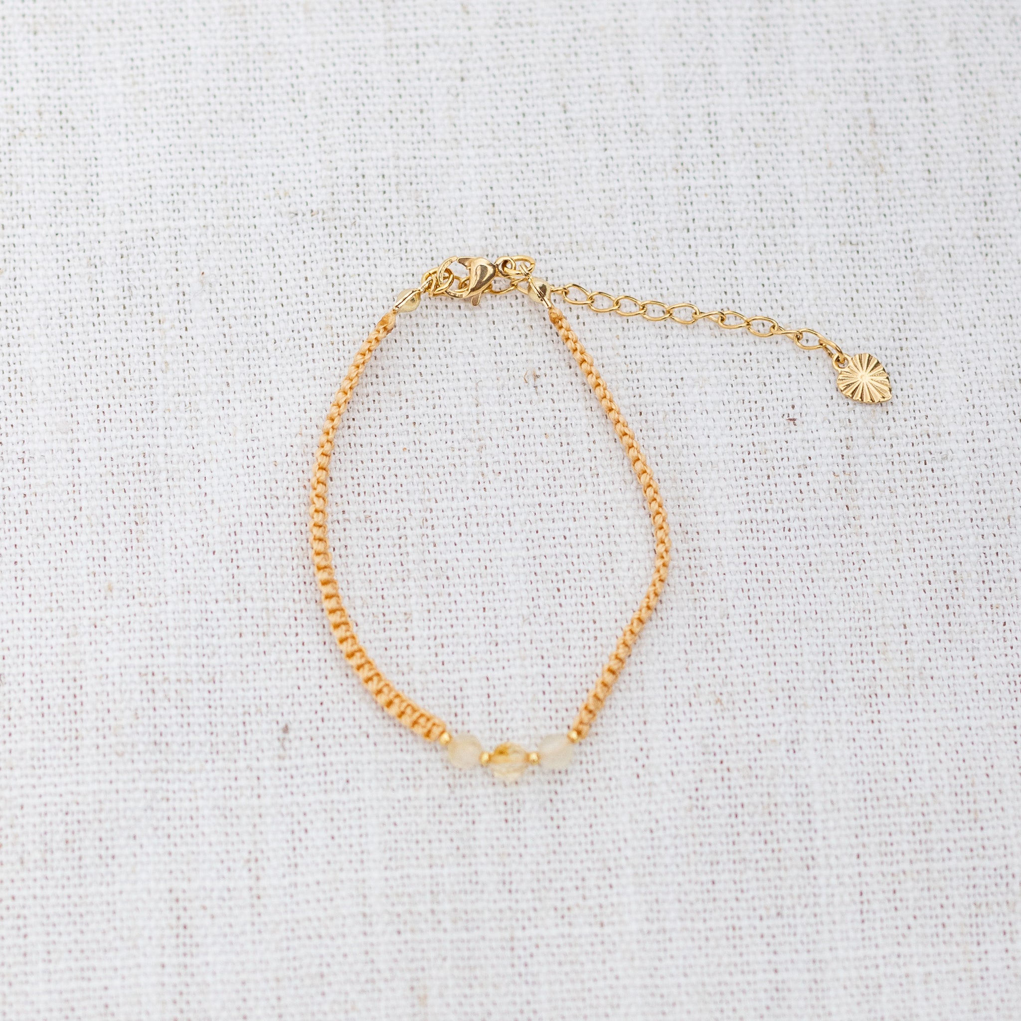 Intuitive Charms Eos's Guard Citrine Braided natural Crystal beaded custom Bracelet in gold and yellow cord and clasp extension on a light fabric background