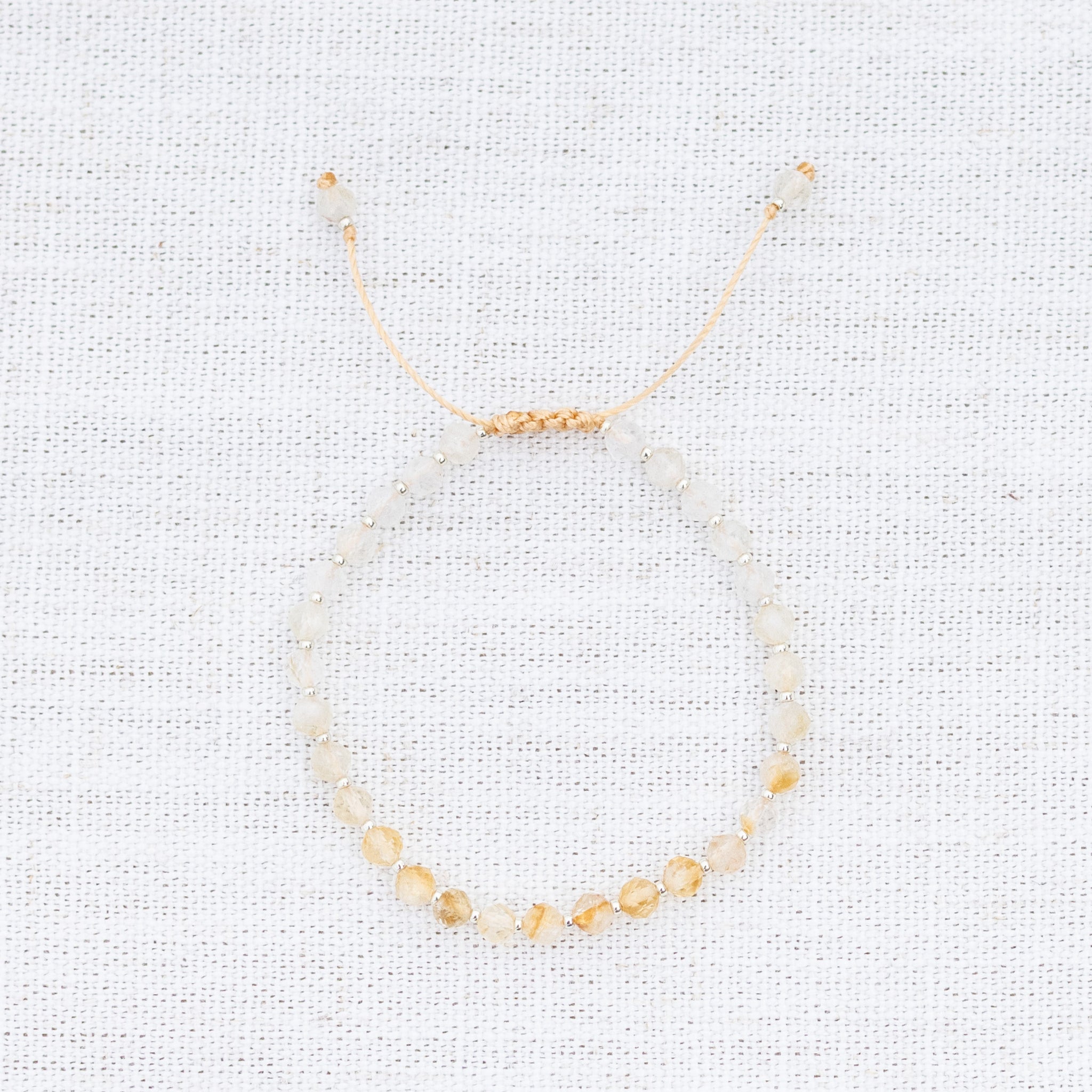 Intuitive Charms Eos's Glow Citrine Braided natural Crystal beaded custom Bracelet in silver and yellow cord on a light fabric background