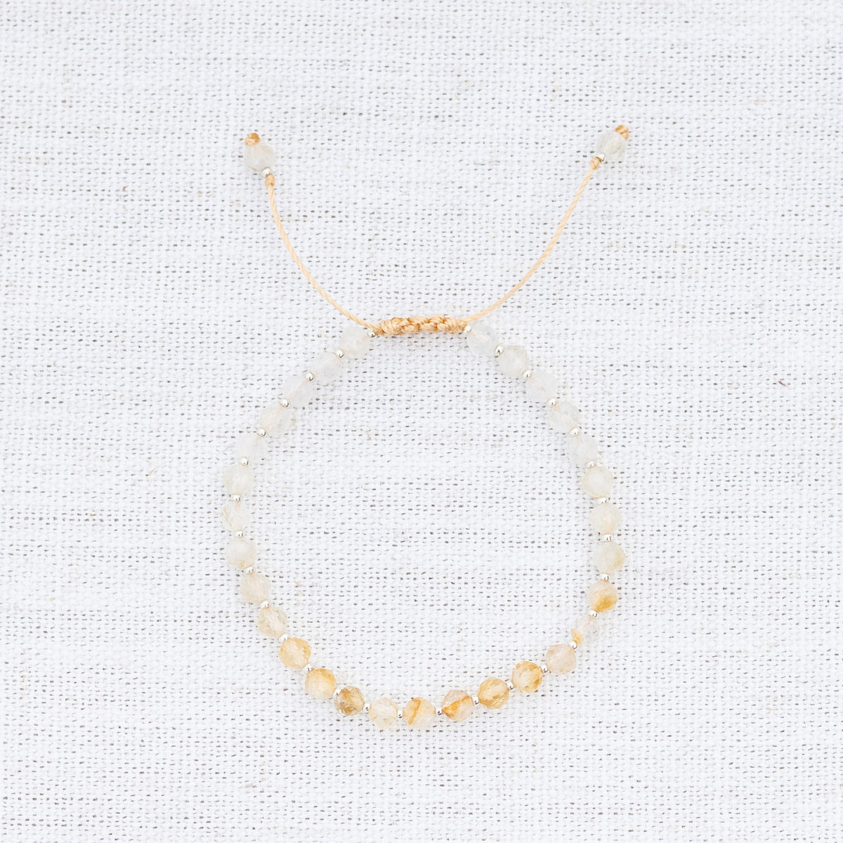 Intuitive Charms Eos's Glow Citrine Braided natural Crystal beaded custom Bracelet in silver and yellow cord on a light fabric background