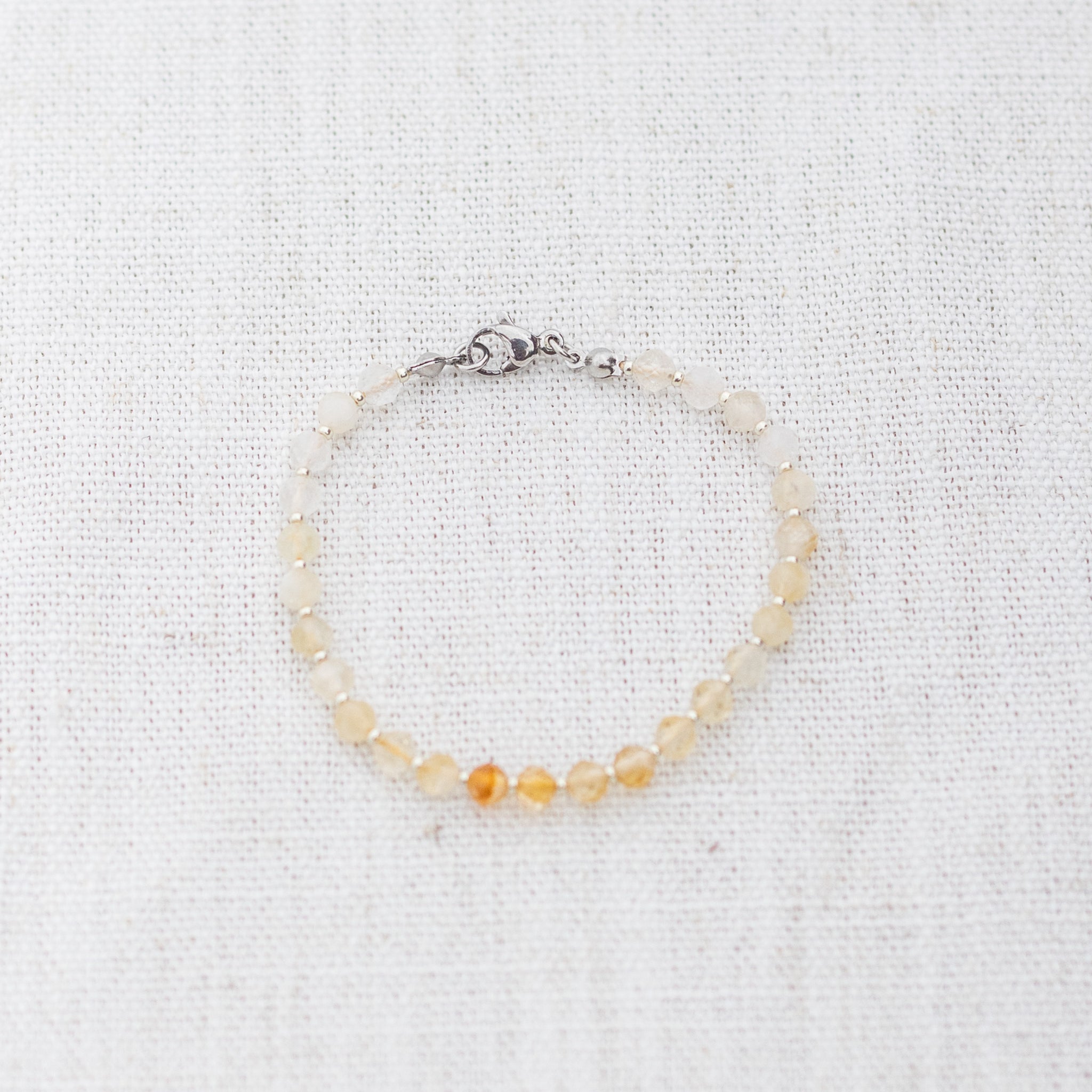 Intuitive Charms Eos's Glow Citrine Braided natural Crystal beaded custom Bracelet in silver and yellow cord and clasp on a light fabric background