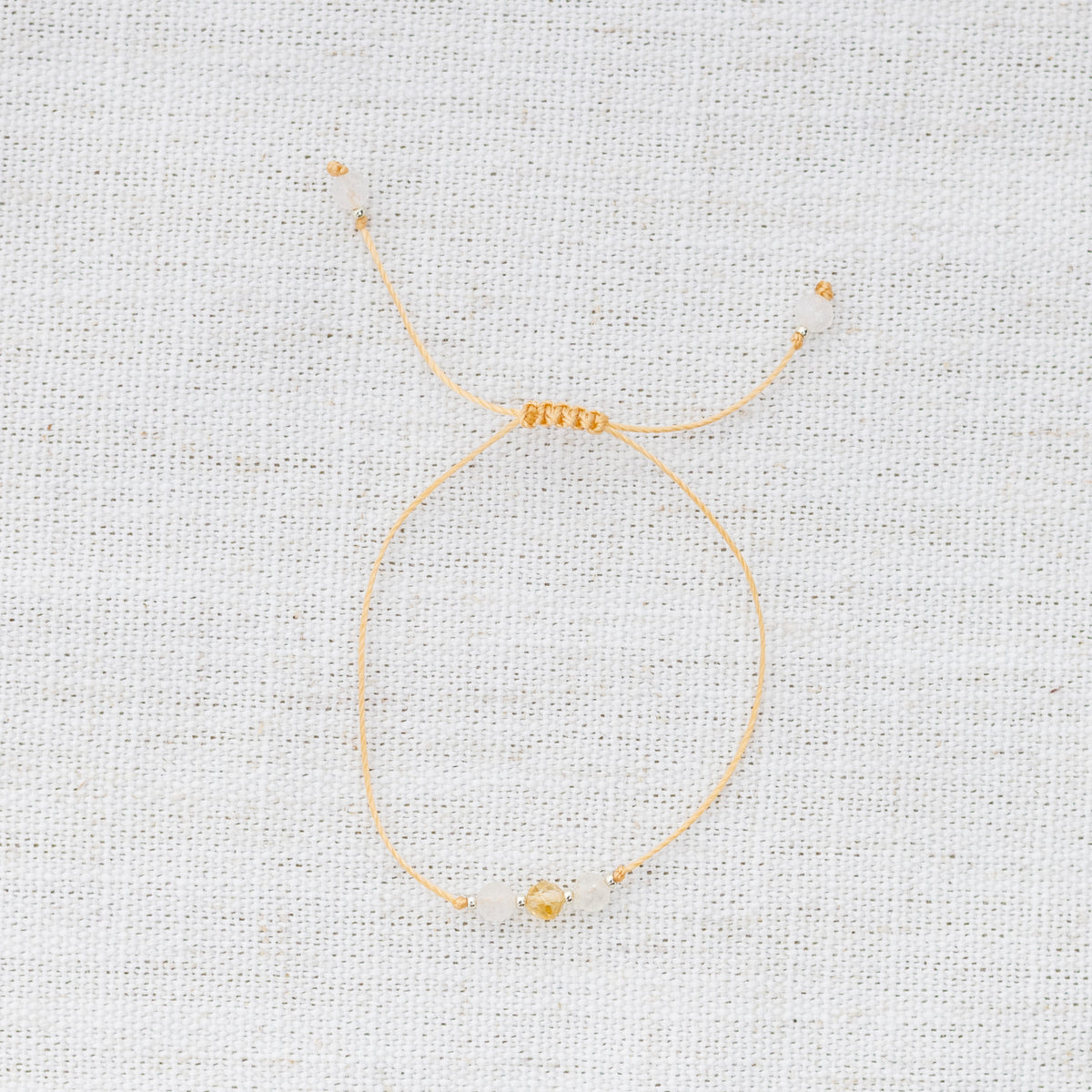 Intuitive Charms Eos's Mist Citrine Braided natural Crystal beaded custom Bracelet in silver and yellow cord on a light fabric background