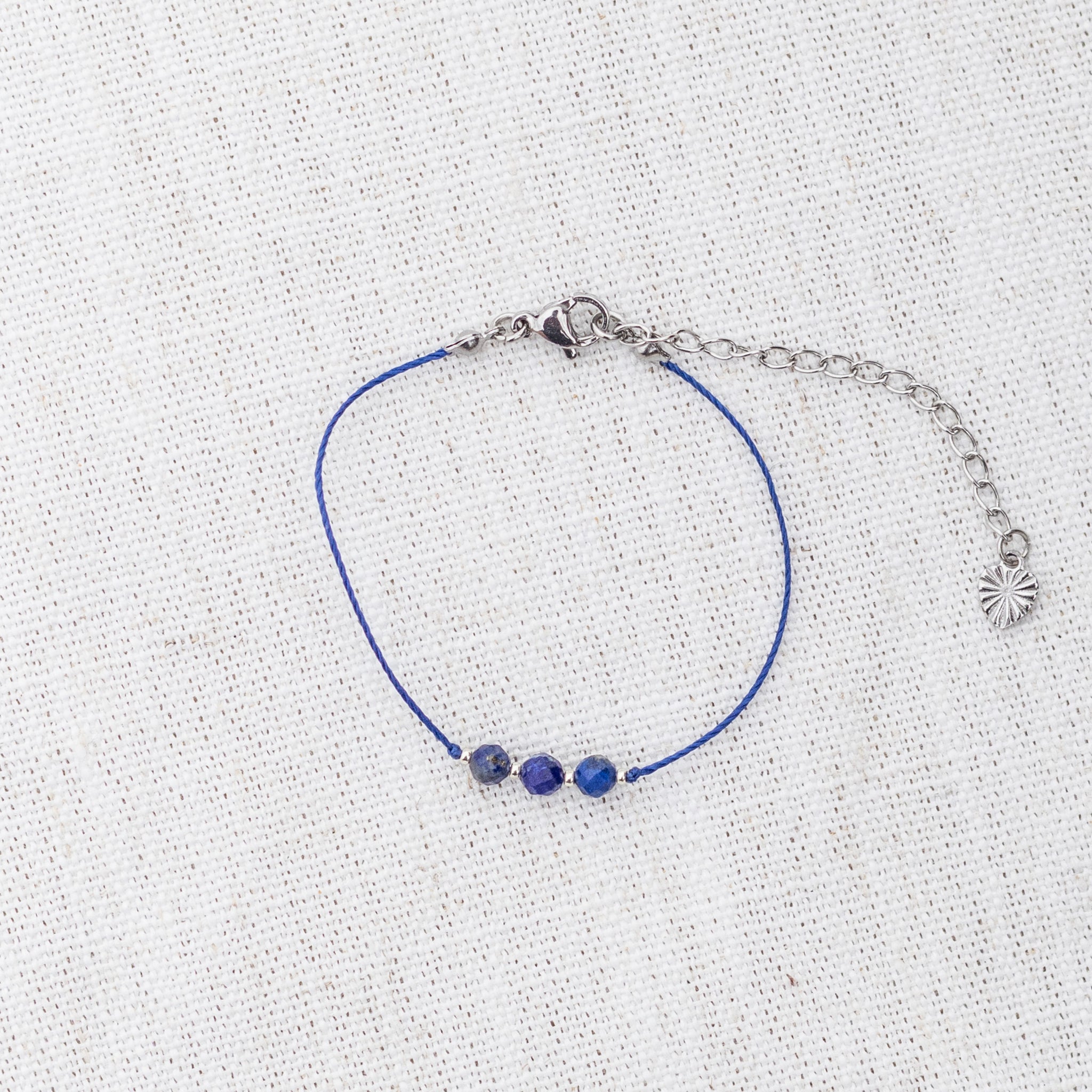 Intuitive Charms Amphitrite's Mist Lapis Lazuli Braided natural Crystal beaded custom Bracelet in silver and deep blue cord and clasp extension on a light fabric background