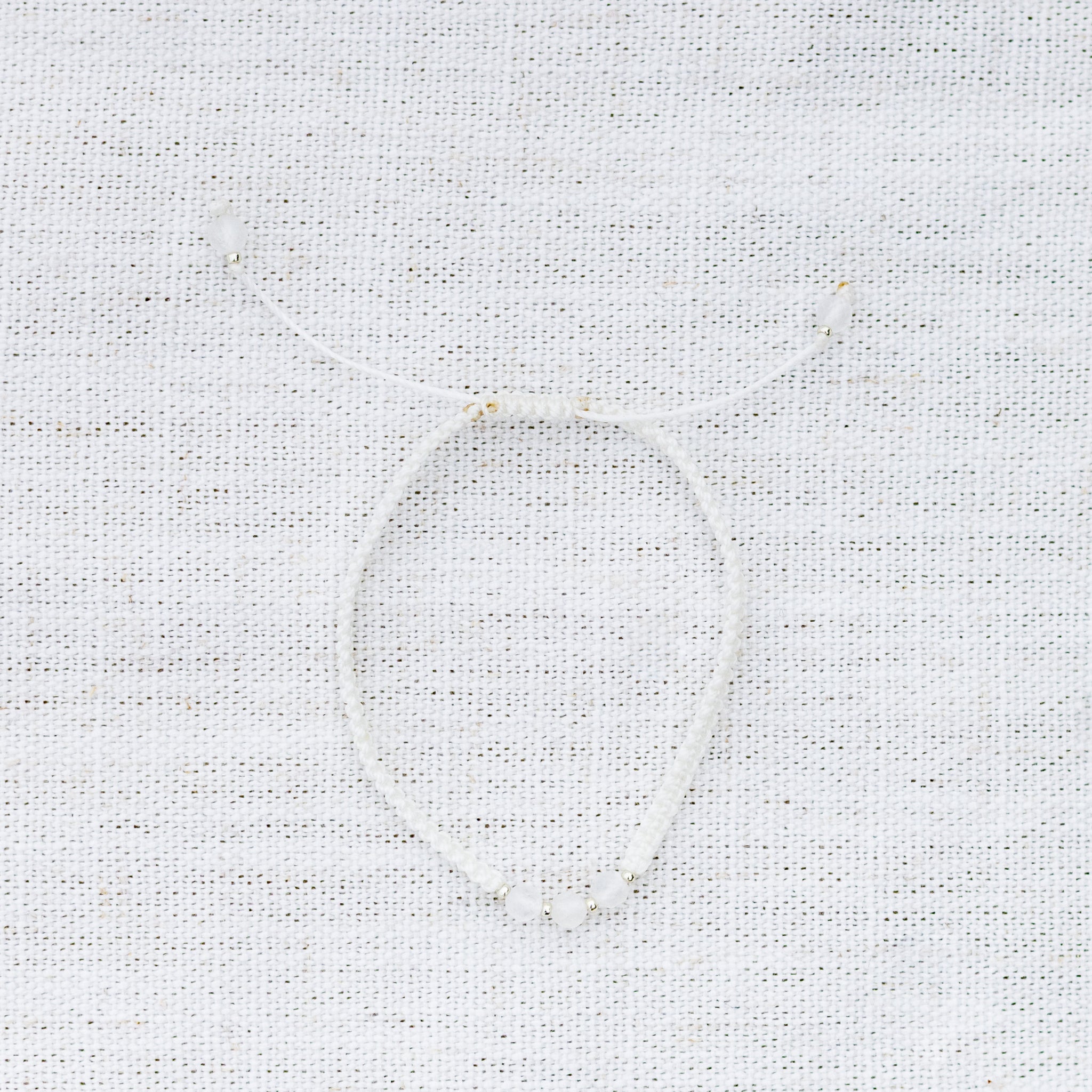 Intuitive Charms Selene's Guard Moonstone Braided natural Crystal beaded custom Bracelet in silver and white cord on a light fabric background