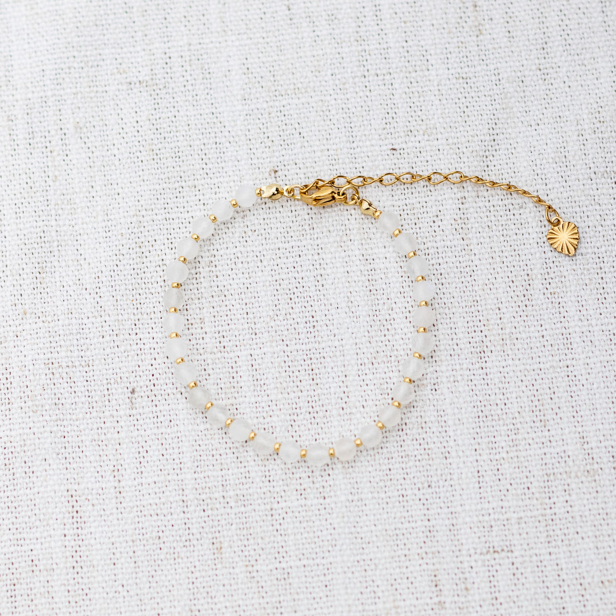 Intuitive Charms Selene's Glow Moonstone Braided natural Crystal beaded custom Bracelet in gold and white cord and clasp extension on a light fabric background