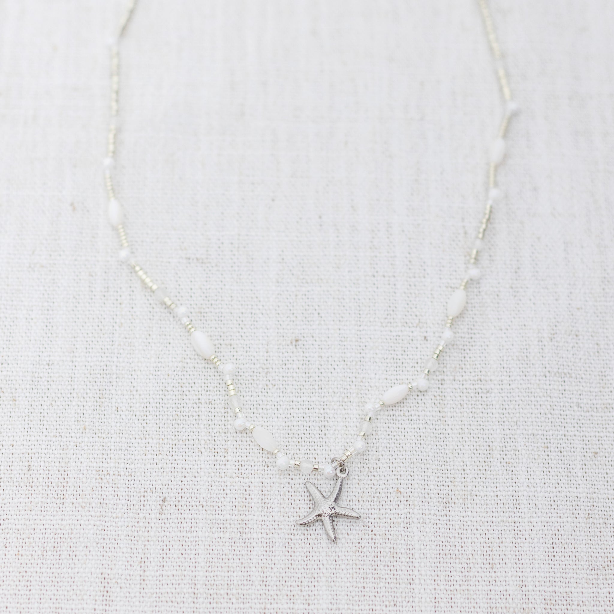 Intuitive Charms Selene's Song Moonstone natural Crystal beaded custom necklace in silver and clasp extension on a light fabric background