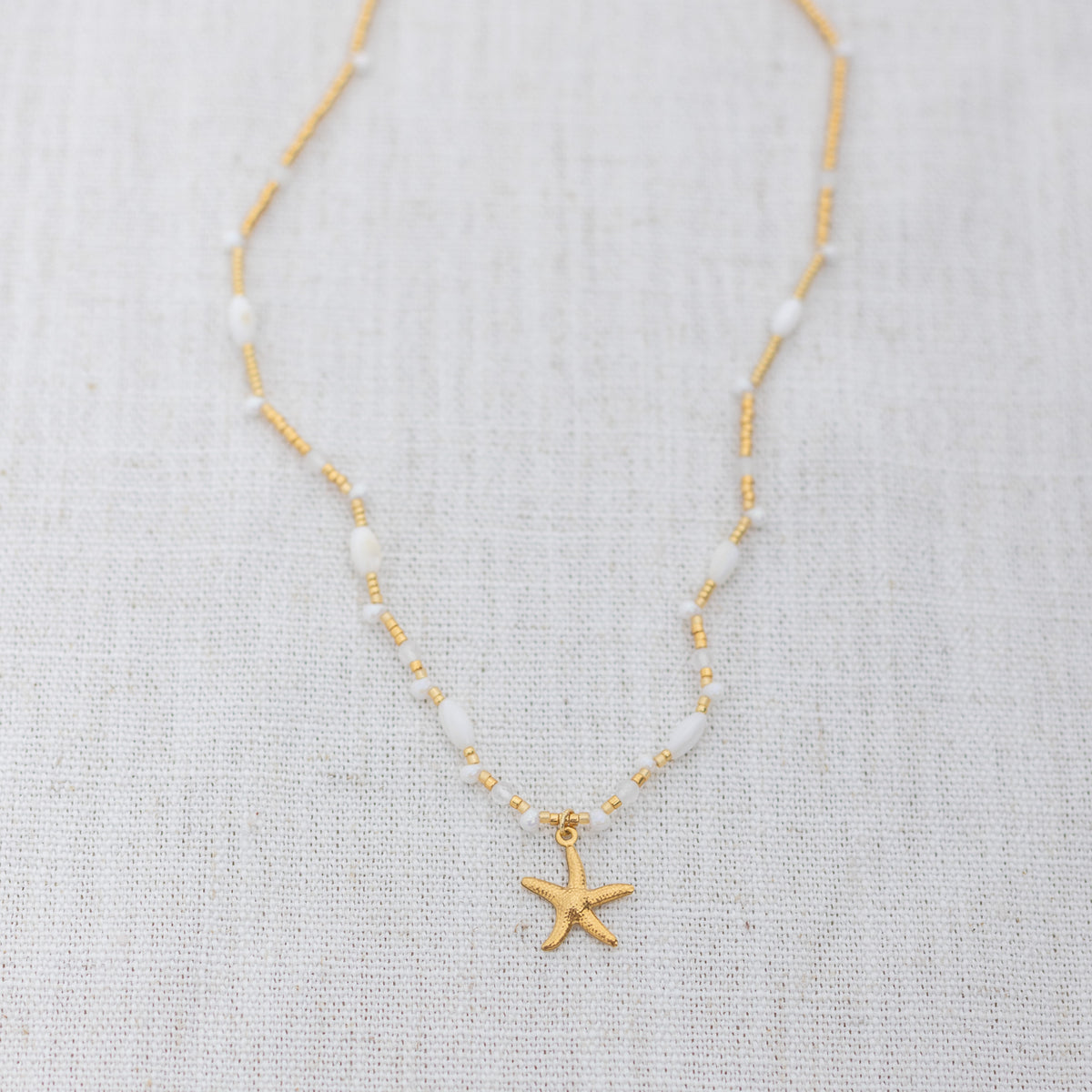 Intuitive Charms Selene's Song Moonstone natural Crystal beaded custom necklace in gold and clasp extension on a light fabric background