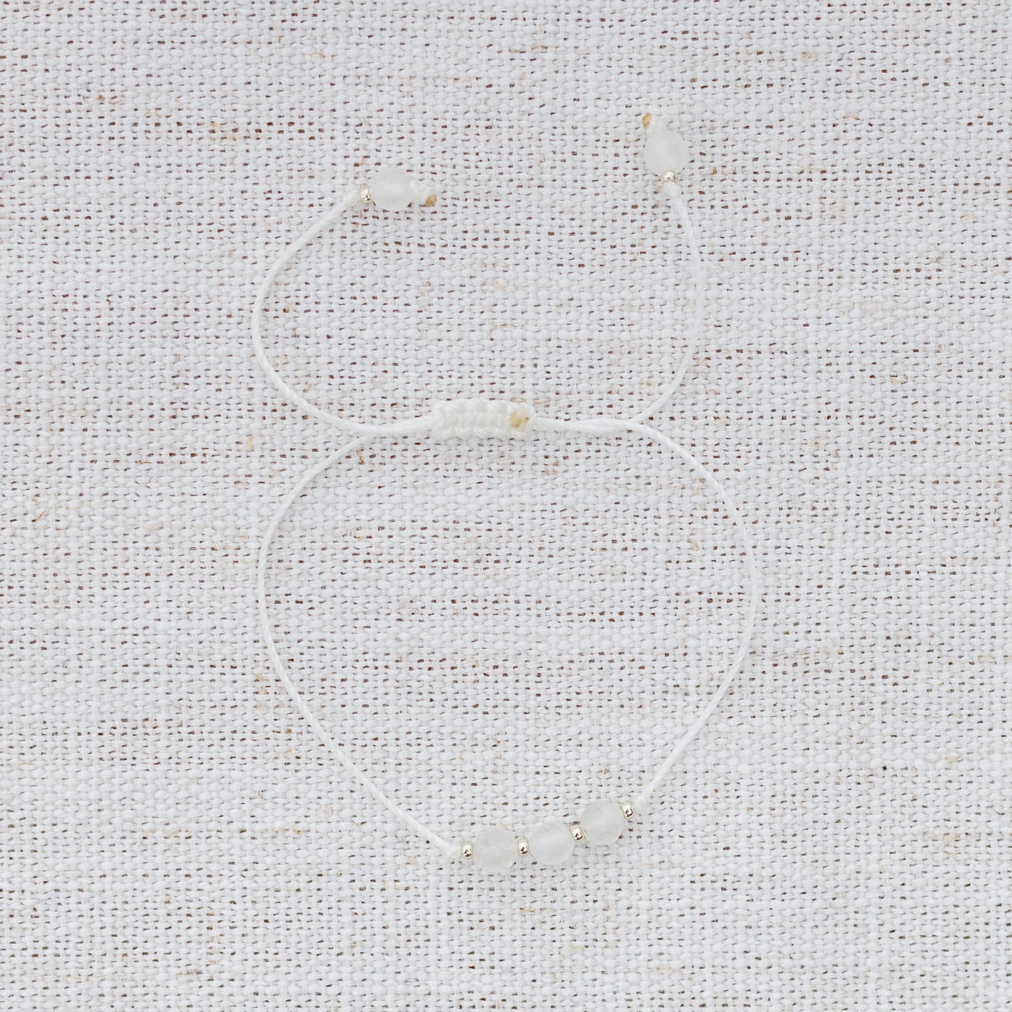 Intuitive Charms Selene's Mist Moonstone Braided natural Crystal beaded custom Bracelet in silver and white cord on a light fabric background