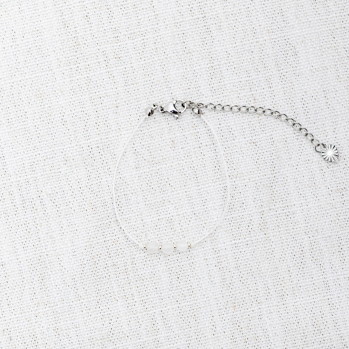 Intuitive Charms Selene's Mist Moonstone Braided natural Crystal beaded custom Bracelet in silver and white cord and clasp extension on a light fabric background