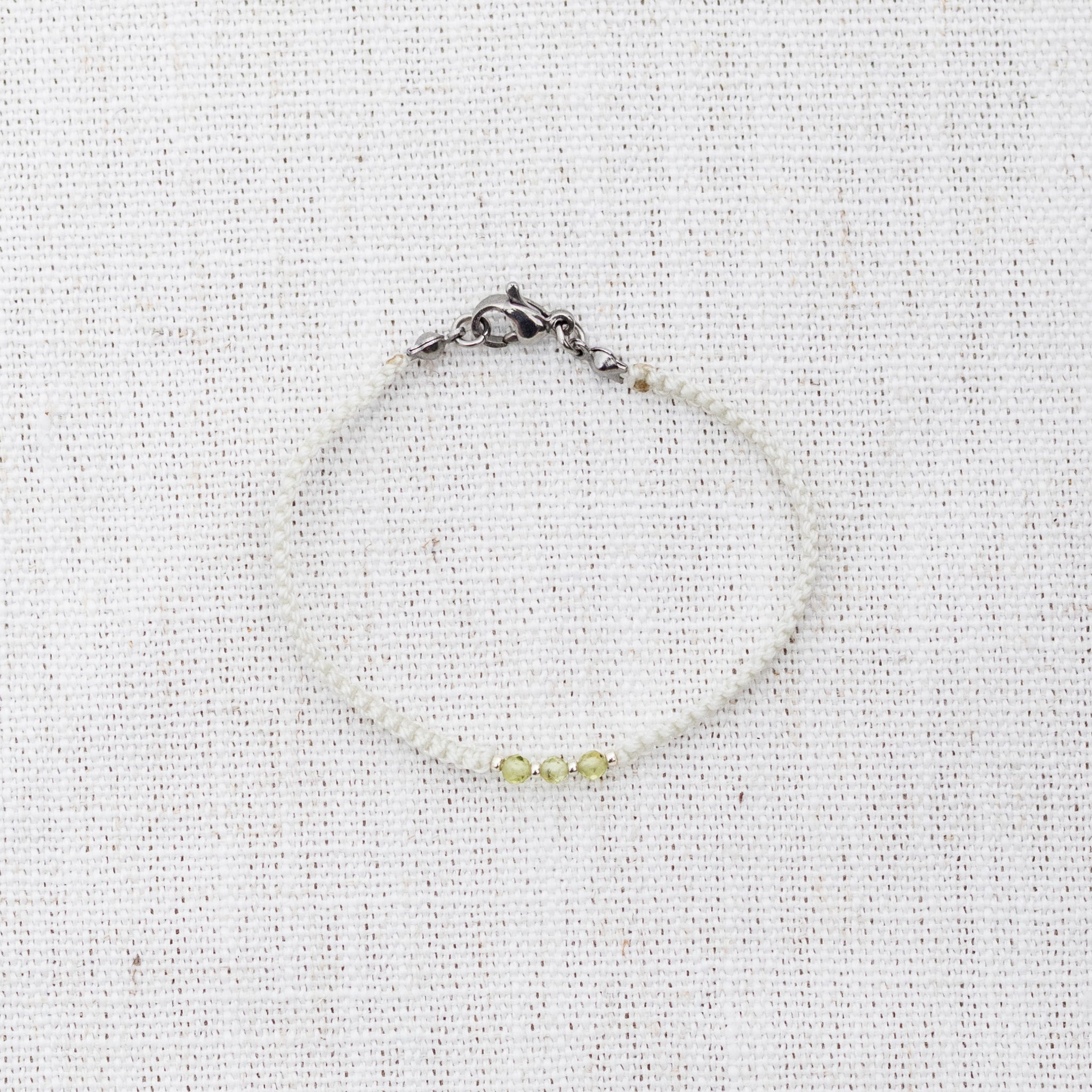 Intuitive Charms Nerina's Guard Peridot Braided natural Crystal beaded custom Bracelet in silver and light mint cord and clasp on a light fabric background