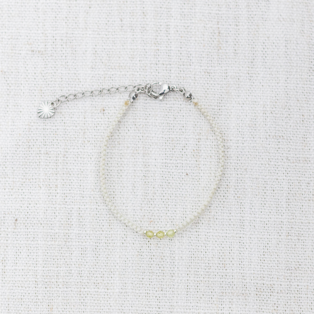 Intuitive Charms Nerina's Guard Peridot Braided natural Crystal beaded custom Bracelet in silver and light mint cord and clasp extension on a light fabric background