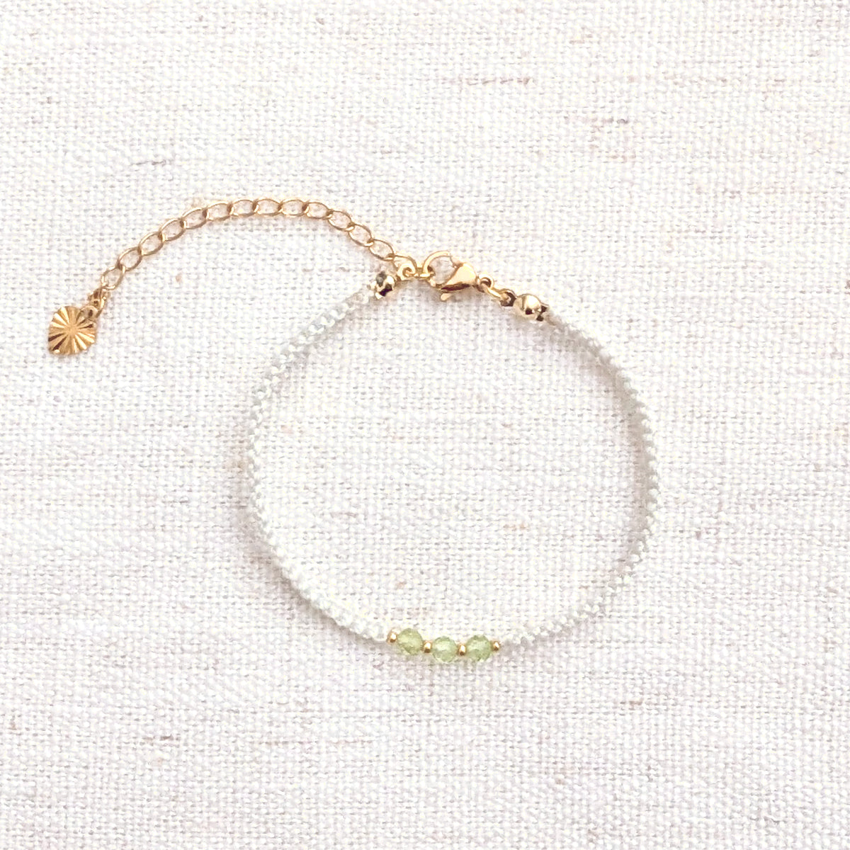 Intuitive Charms Nerina's Guard Peridot Braided natural Crystal beaded custom Bracelet in gold and light mint cord and clasp extension on a light fabric background