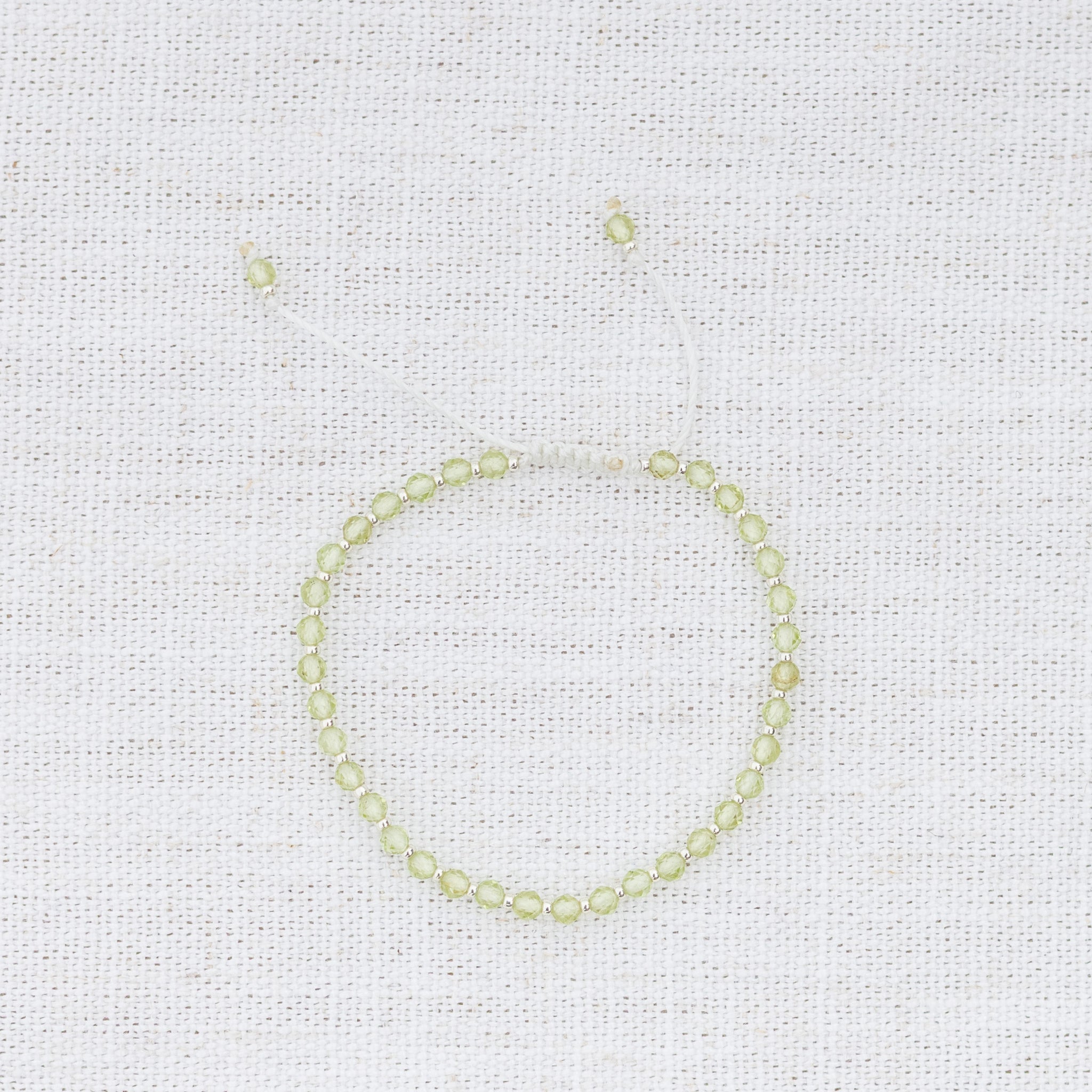 Intuitive Charms Nerina's Glow Peridot Braided natural Crystal beaded custom Bracelet in silver and light mint cord on a light fabric background