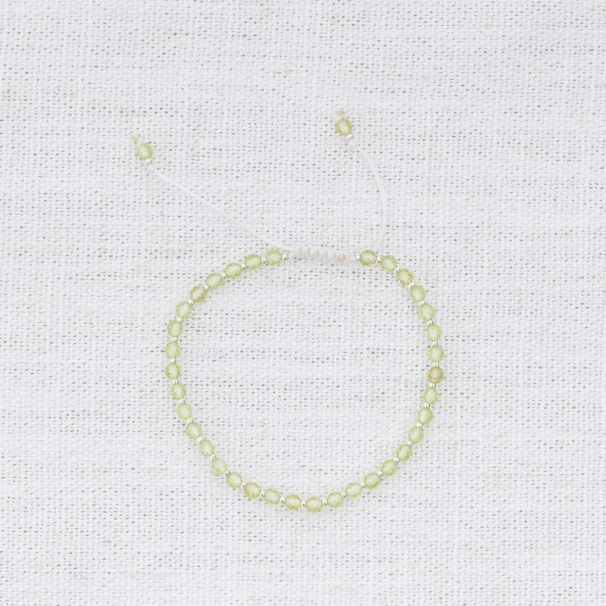 Intuitive Charms Nerina's Glow Peridot Braided natural Crystal beaded custom Bracelet in silver and light mint cord on a light fabric background