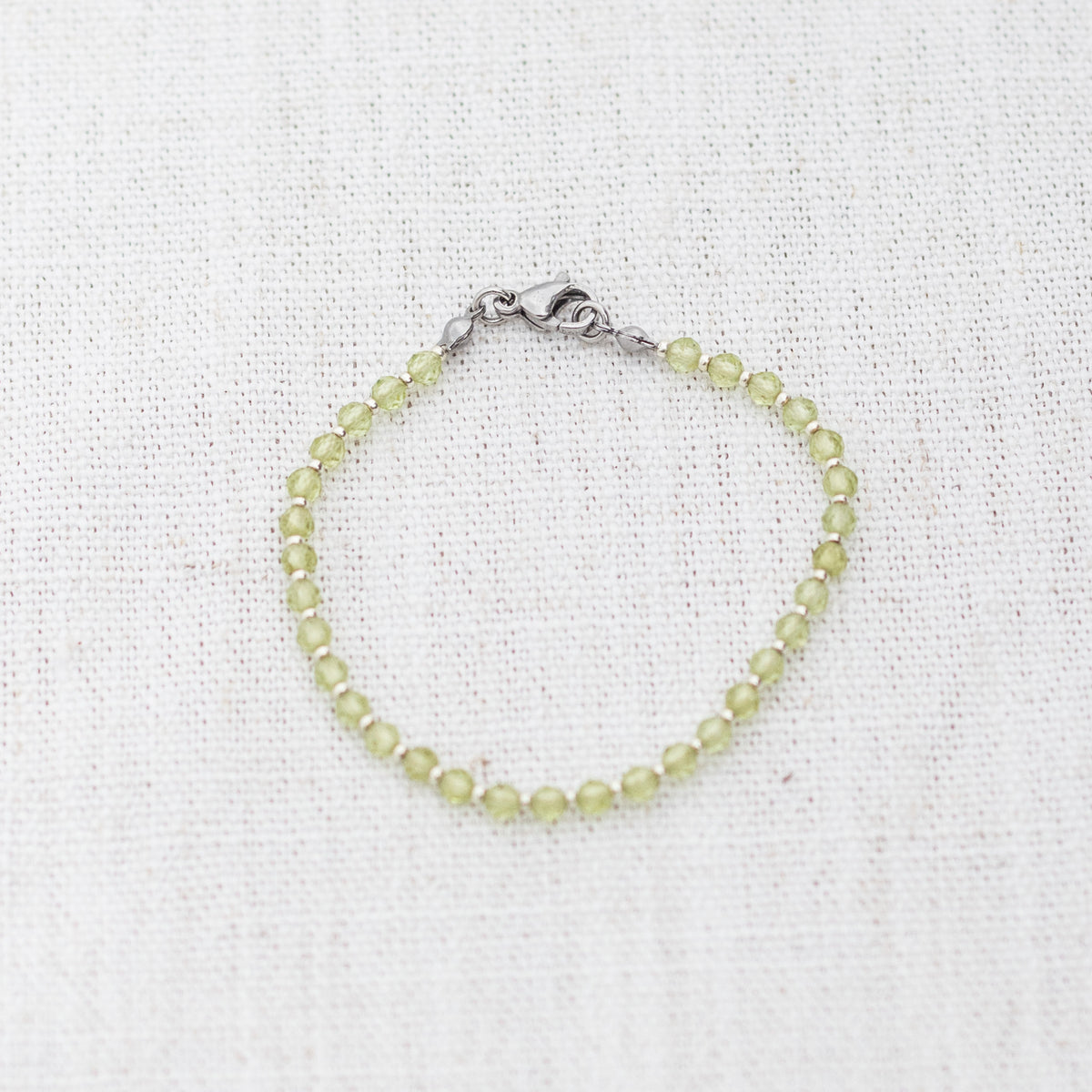 Intuitive Charms Nerina's Glow Peridot Braided natural Crystal beaded custom Bracelet in silver and light mint cord and clasp on a light fabric background