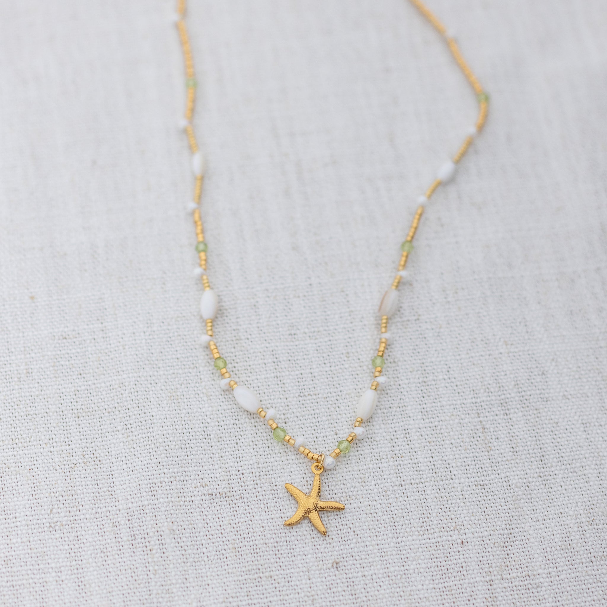 Intuitive Charms Nerina's Song Peridot natural Crystal beaded custom Bracelet in gold on a light fabric background