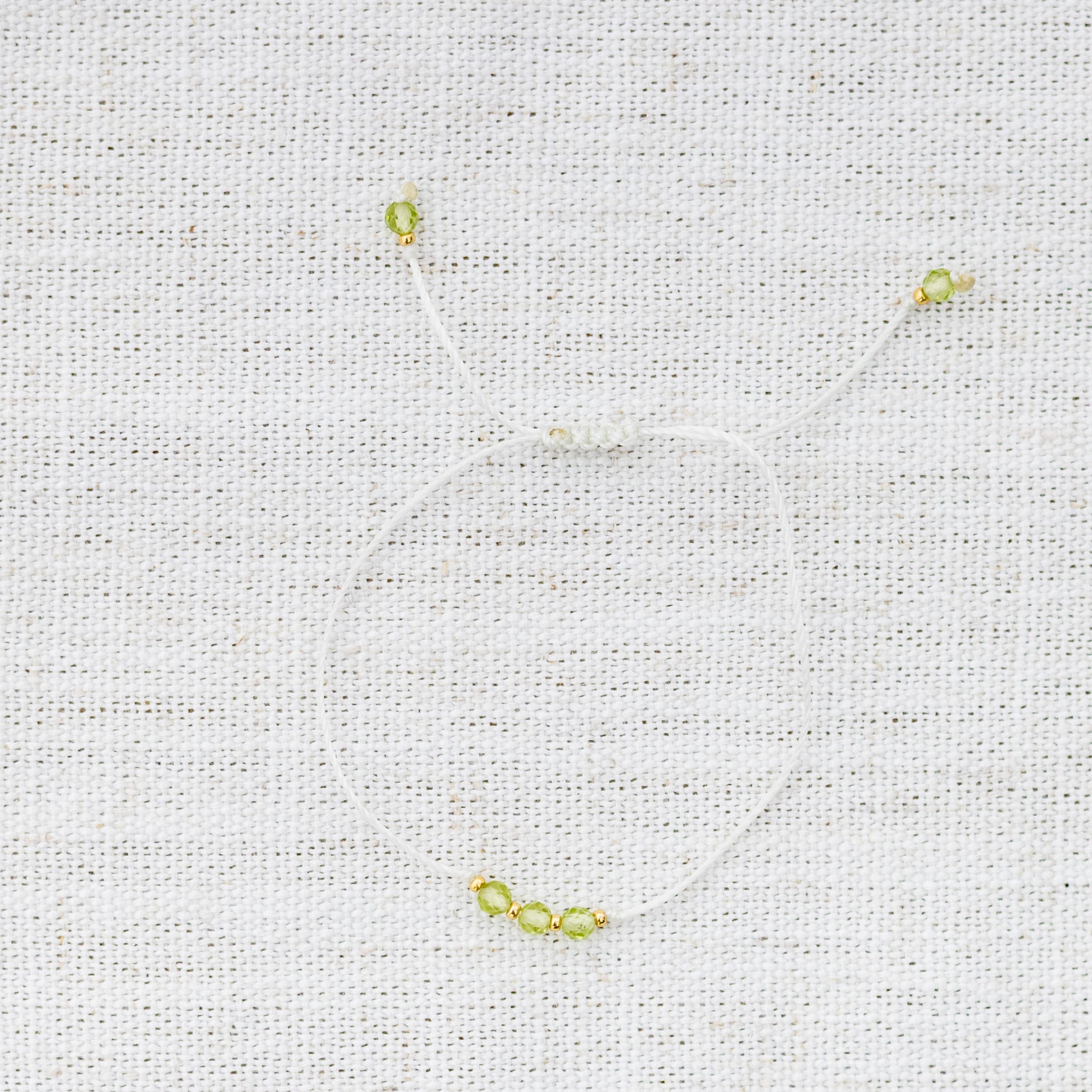 Intuitive Charms Nerina's Mist Peridot Braided natural Crystal beaded custom Bracelet in gold and light mint cord on a light fabric background