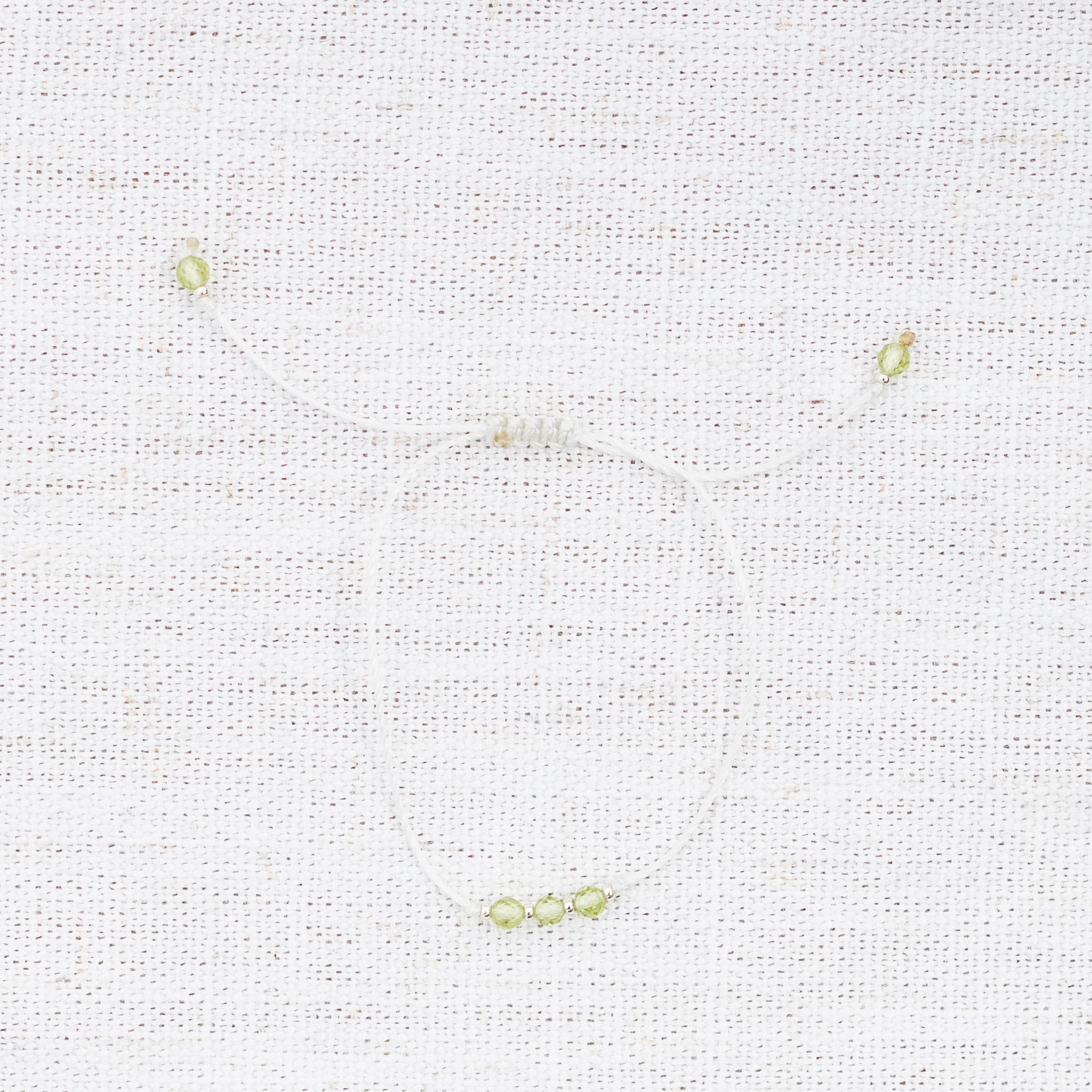 Intuitive Charms Nerina's Mist Peridot Braided natural Crystal beaded custom Bracelet in silver and light mint cord on a light fabric background