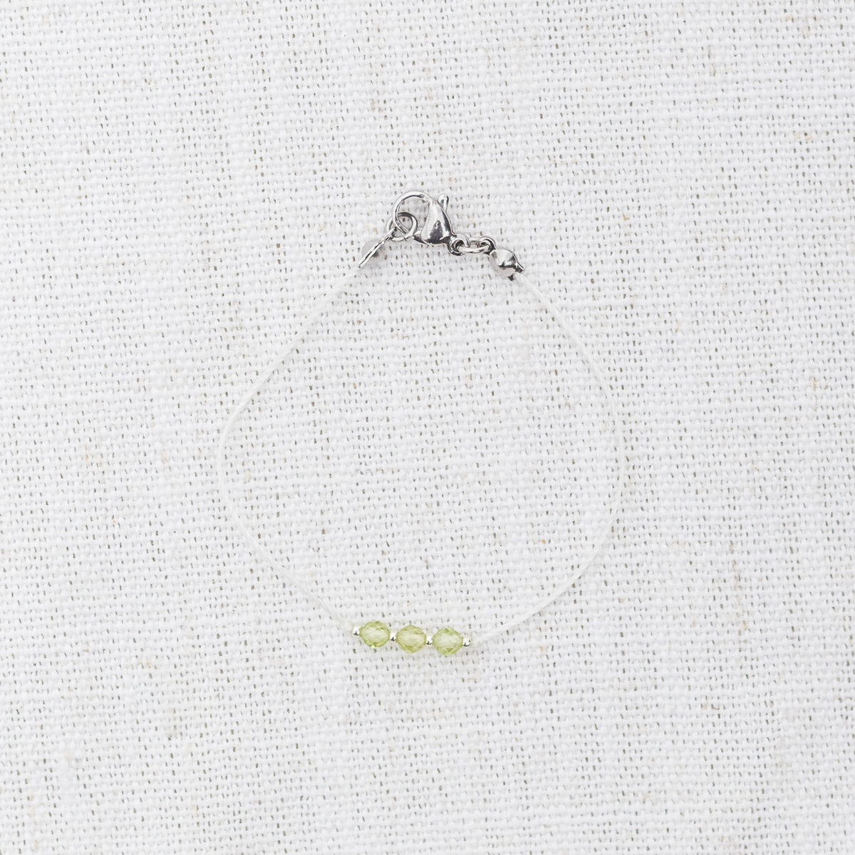 Intuitive Charms Nerina's Mist Peridot Braided natural Crystal beaded custom Bracelet in silver and light mint cord and clasp on a light fabric background