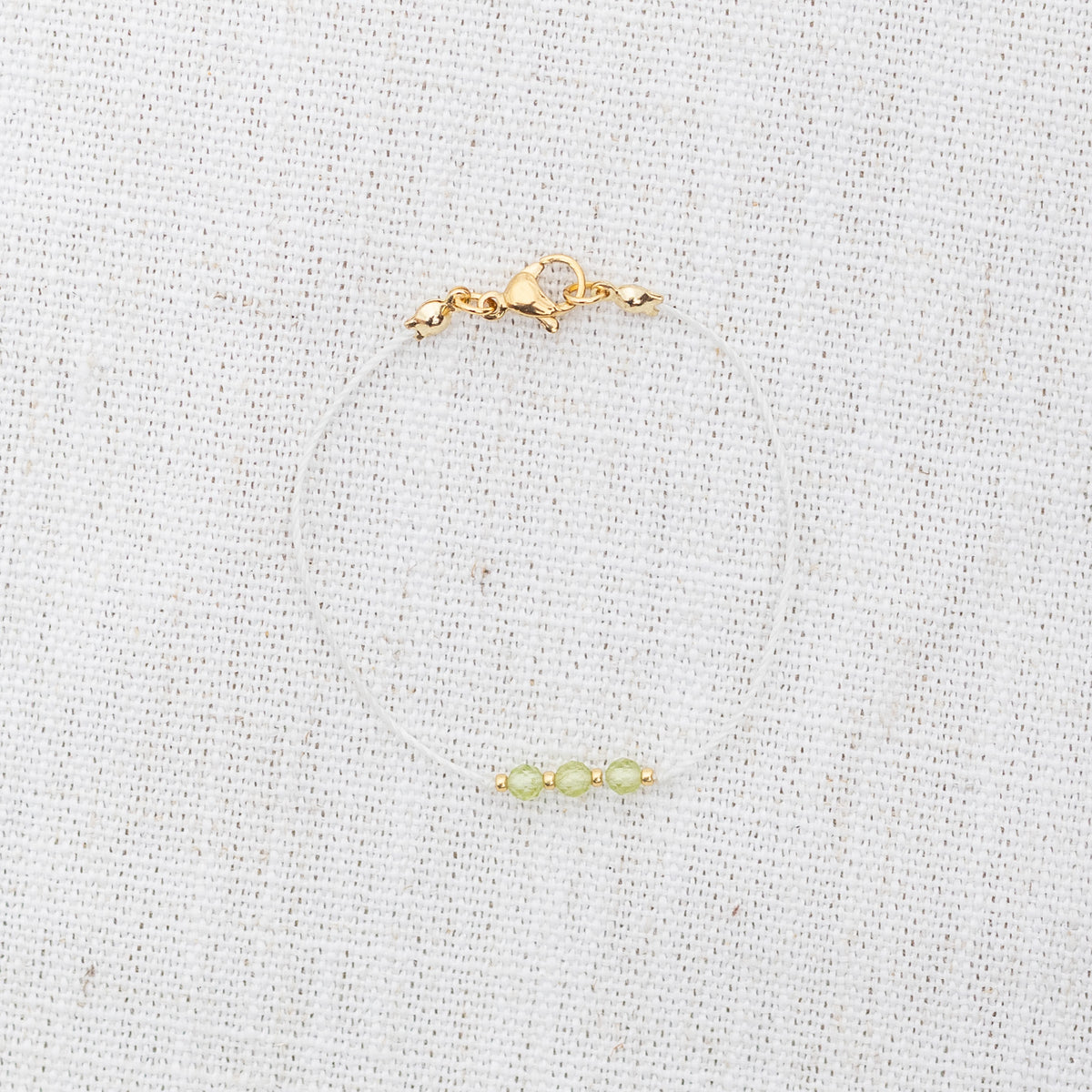 Intuitive Charms Nerina's Mist Peridot Braided natural Crystal beaded custom Bracelet in gold and light mint cord and clasp on a light fabric background