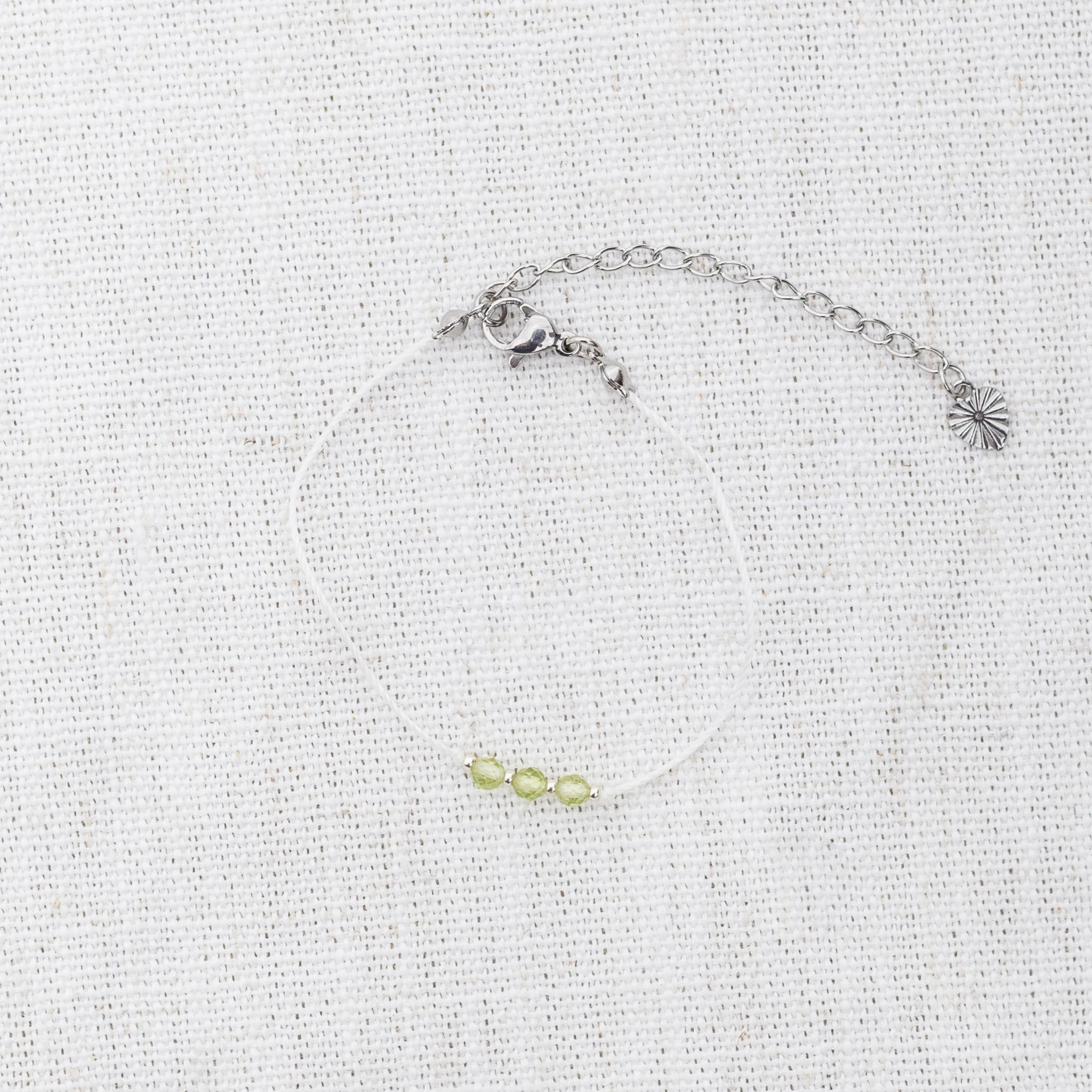 Intuitive Charms Nerina's Mist Peridot Braided natural Crystal beaded custom Bracelet in silver and light mint cord and clasp extension on a light fabric background