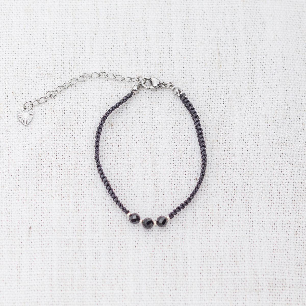 Intuitive Charms Ceto's Guard Black tourmaline Braided natural Crystal beaded custom Bracelet in silver and black cord and clasp extension on a light fabric background