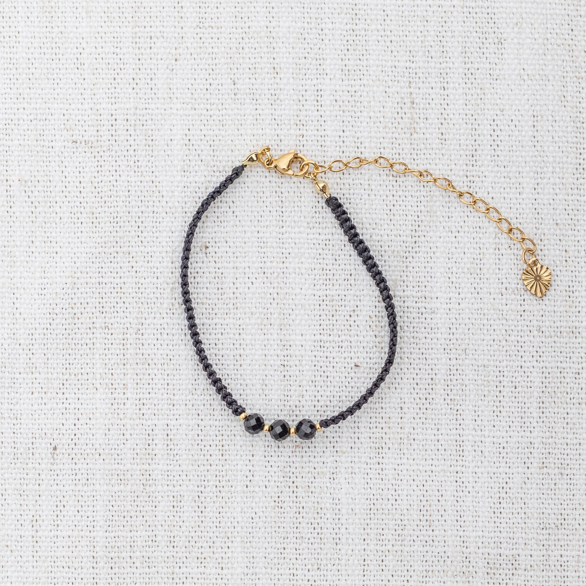 Intuitive Charms Ceto's Guard Black tourmaline Braided natural Crystal beaded custom Bracelet in gold and black cord and clasp extension on a light fabric background