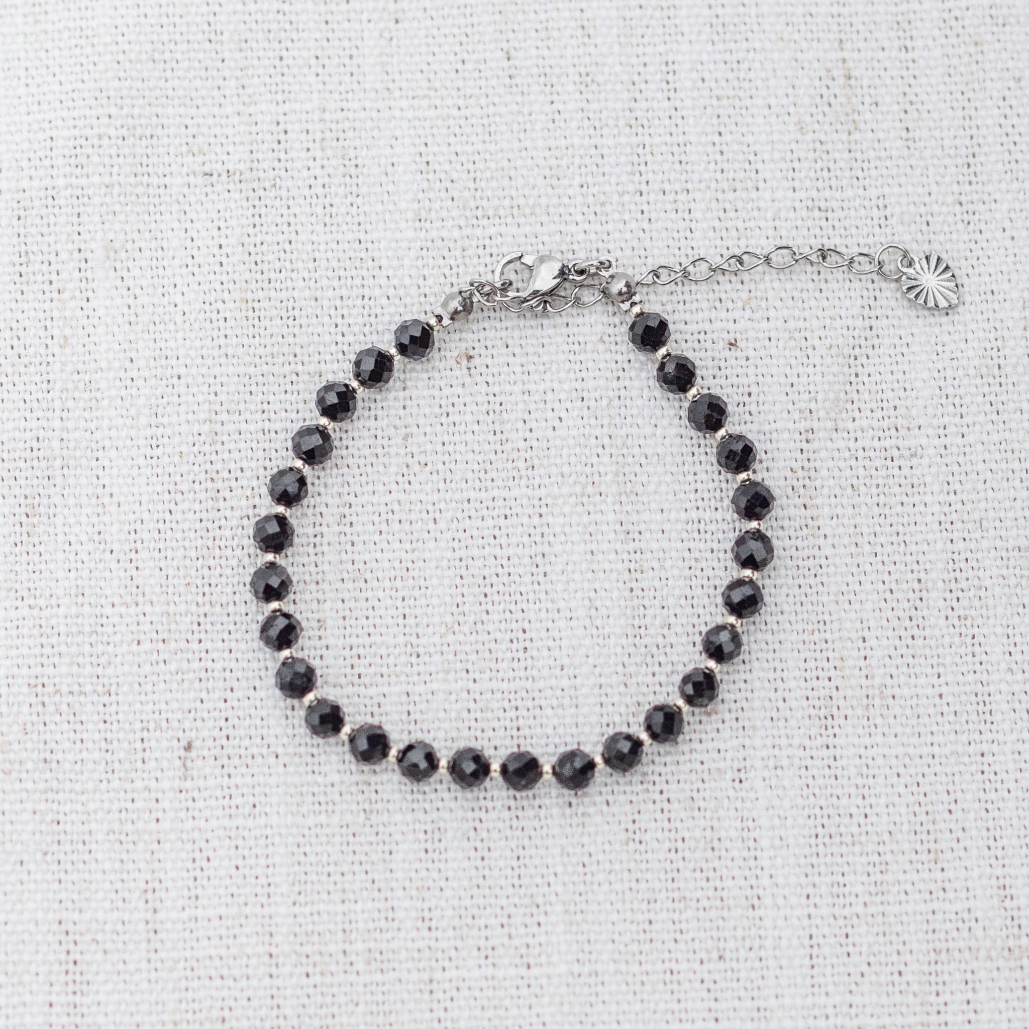 Intuitive Charms Ceto's Glow Apatite Braided natural Crystal beaded custom Bracelet in silver and black cord and clasp extension on a light fabric background