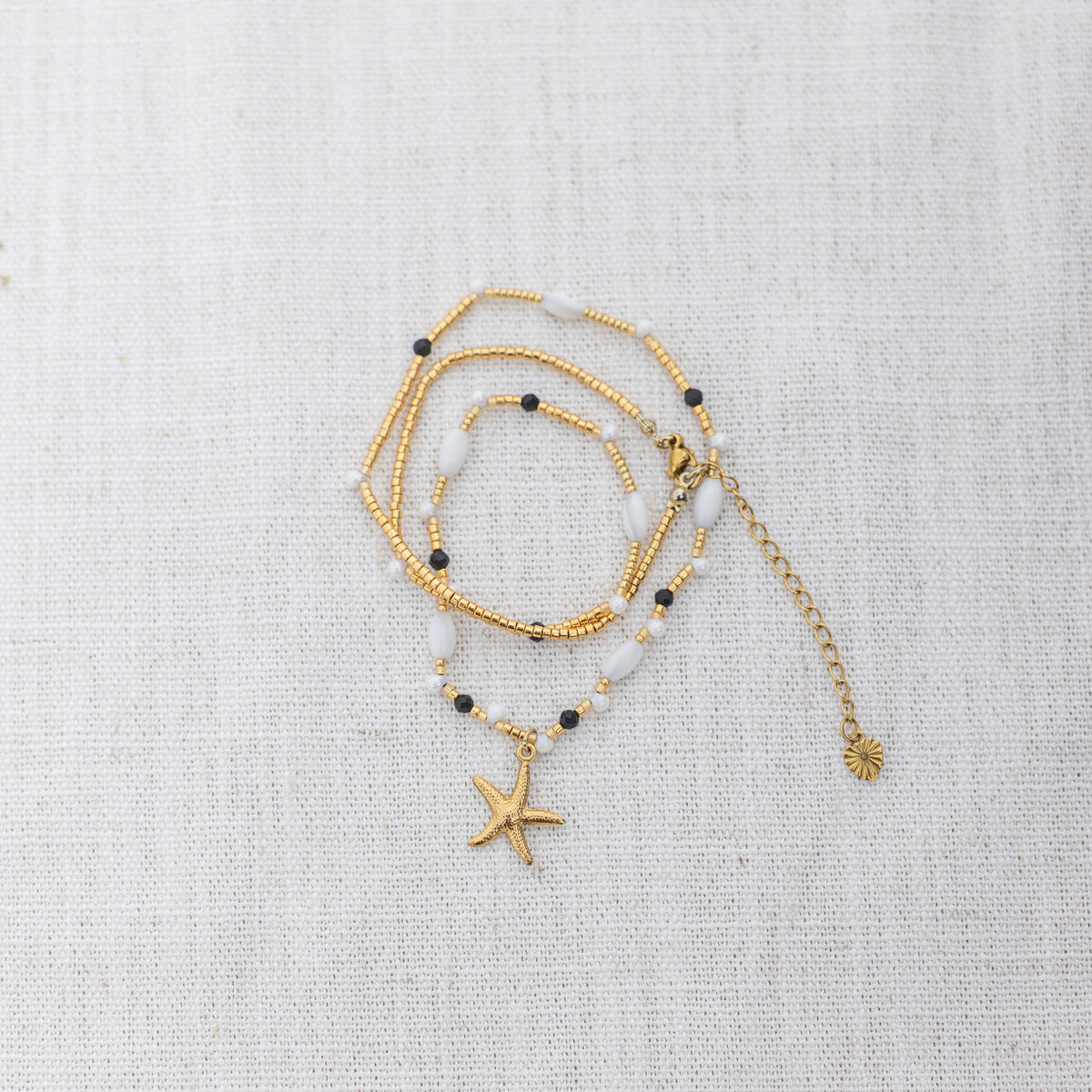 Intuitive Charms Ceto's Song Black tourmaline Braided natural Crystal beaded custom necklace in gold and black cord on a light fabric background wrapped version