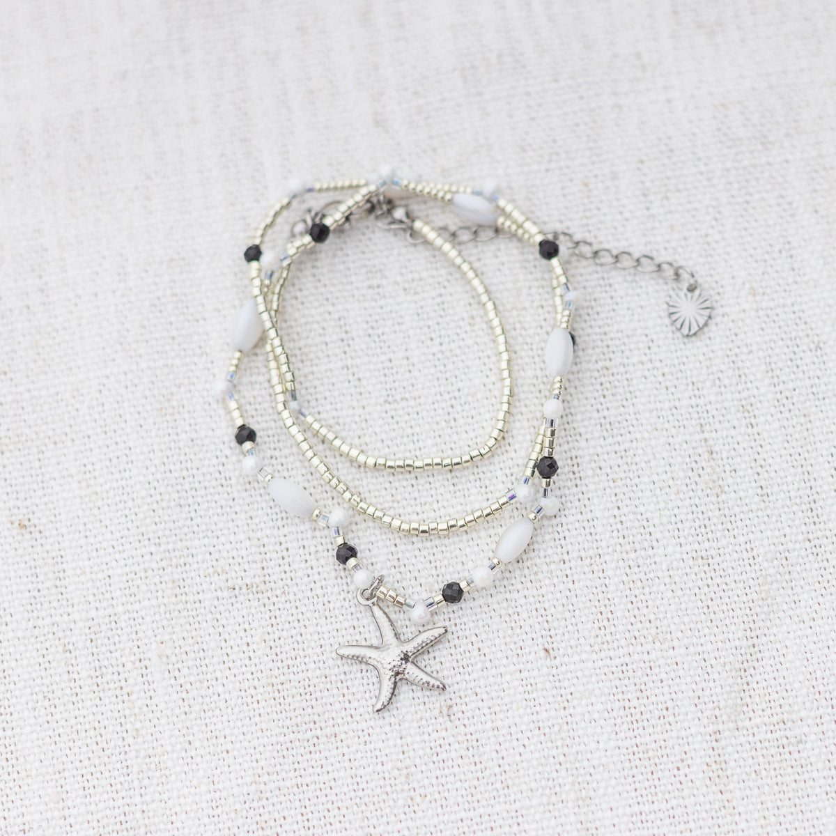 Intuitive Charms Ceto's Song Black tourmaline Braided natural Crystal beaded custom necklace in silver and black cord on a light fabric background wrapped version