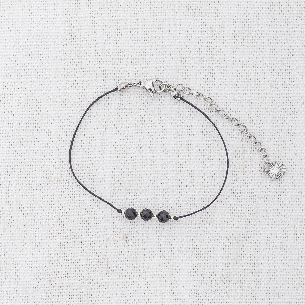 Intuitive Charms Ceto's Mist Black tourmaline Braided natural Crystal beaded custom Bracelet in silver and black cord and clasp extension on a light fabric background
