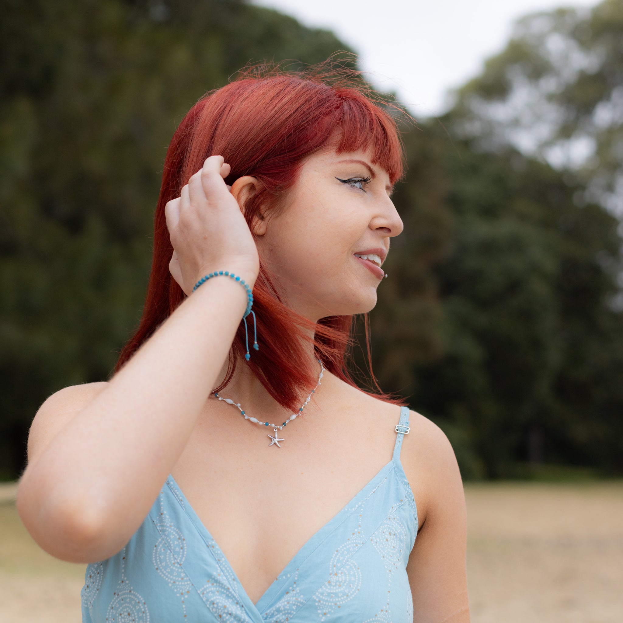 Intuitive Charms Delphina's Glow Apatite Braided natural Crystal beaded custom Bracelet in silver and blue cord on a model looking right and necklace