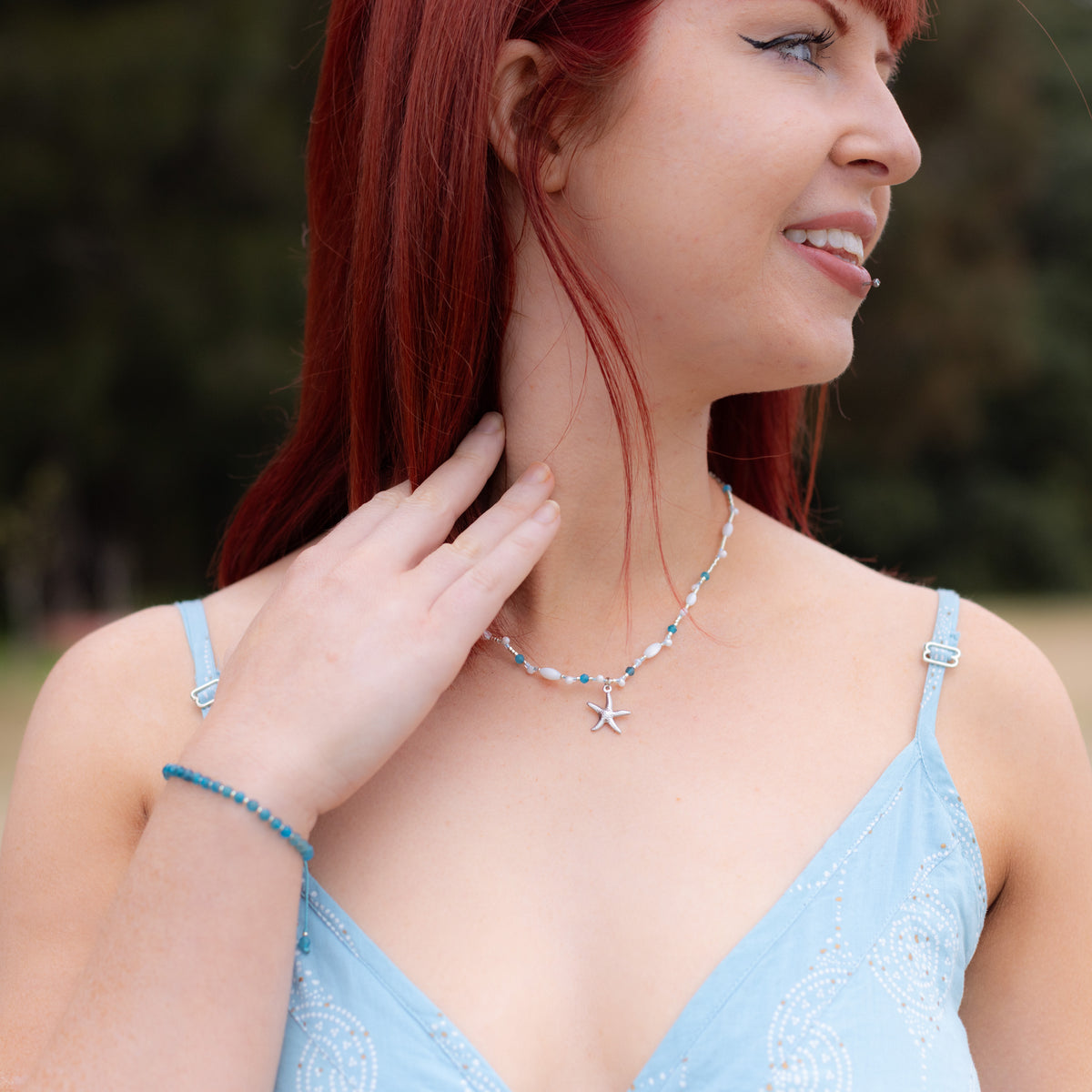 Intuitive Charms Delphina's Glow Apatite Braided natural Crystal beaded custom Bracelet in silver and blue cord on a model looking right zoomed up