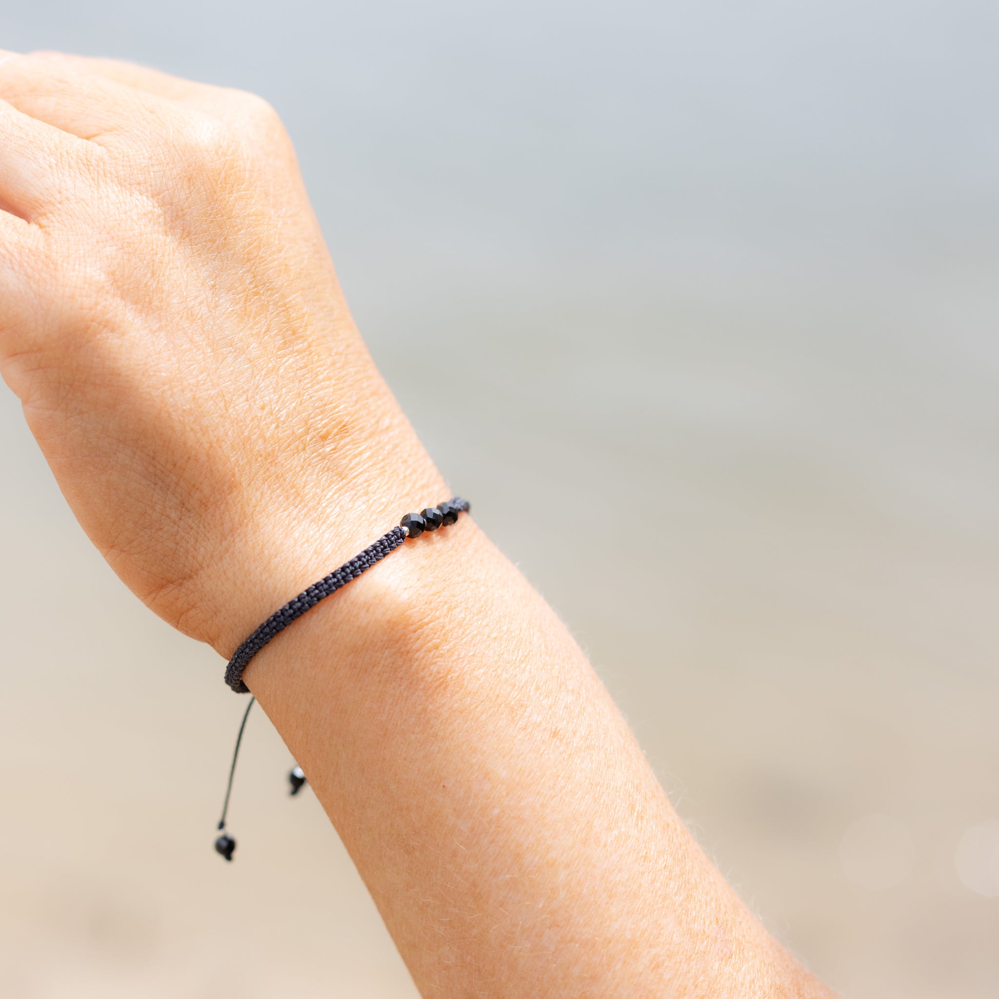 Intuitive Charms Ceto's Guard Black tourmaline Braided natural Crystal beaded custom Bracelet in silver and black cord on a hand model