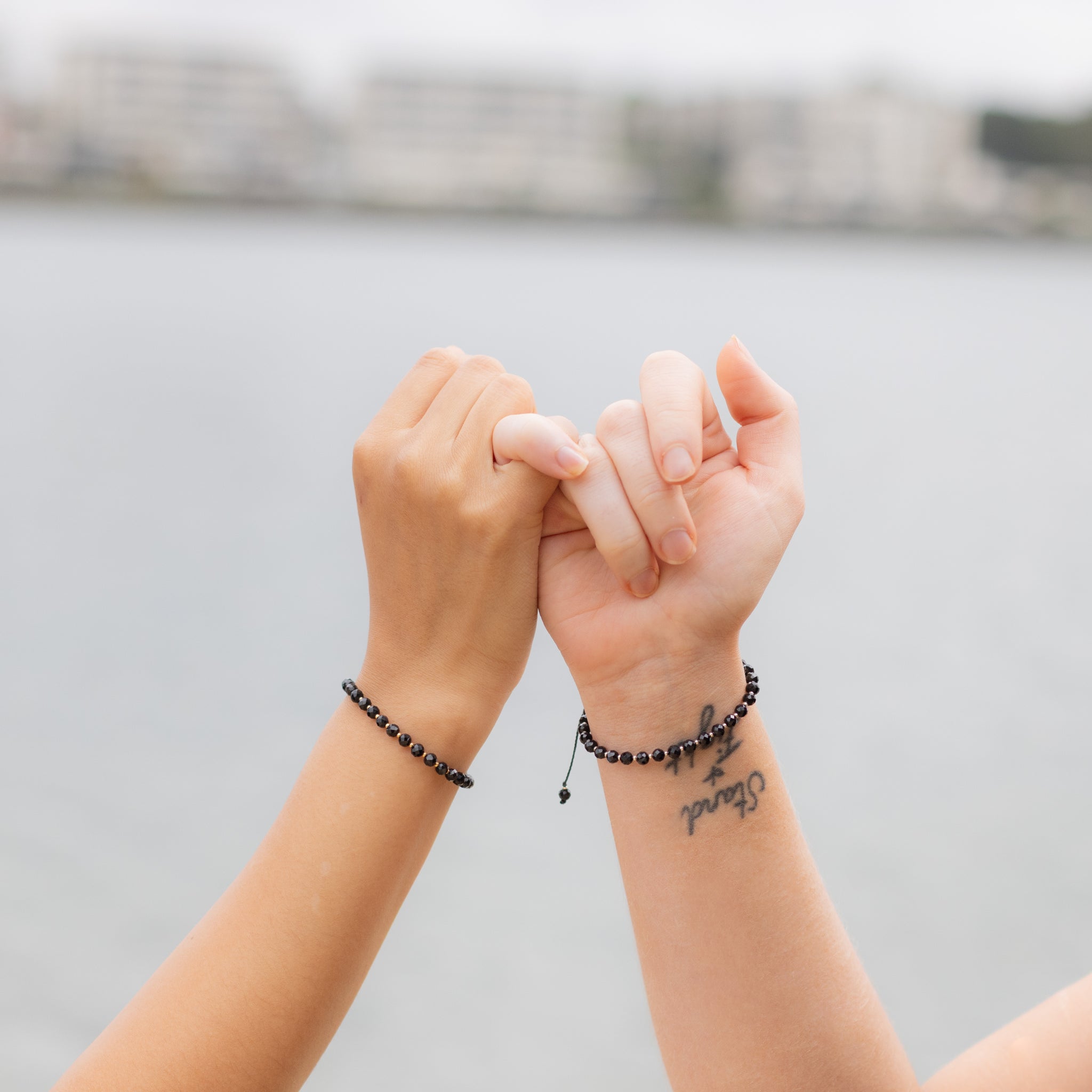 Intuitive Charms Ceto's Glow Apatite Braided natural Crystal beaded custom Bracelet in silver and black cord on two hand model pinky promise with golden version